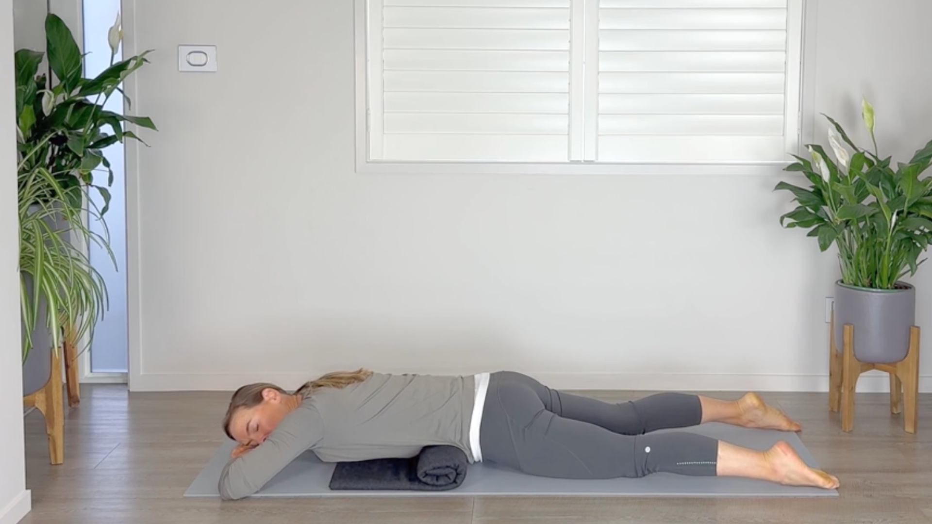 Woman lying on her stomach in a yoga pose with a yoga blanket draped under her front hip points