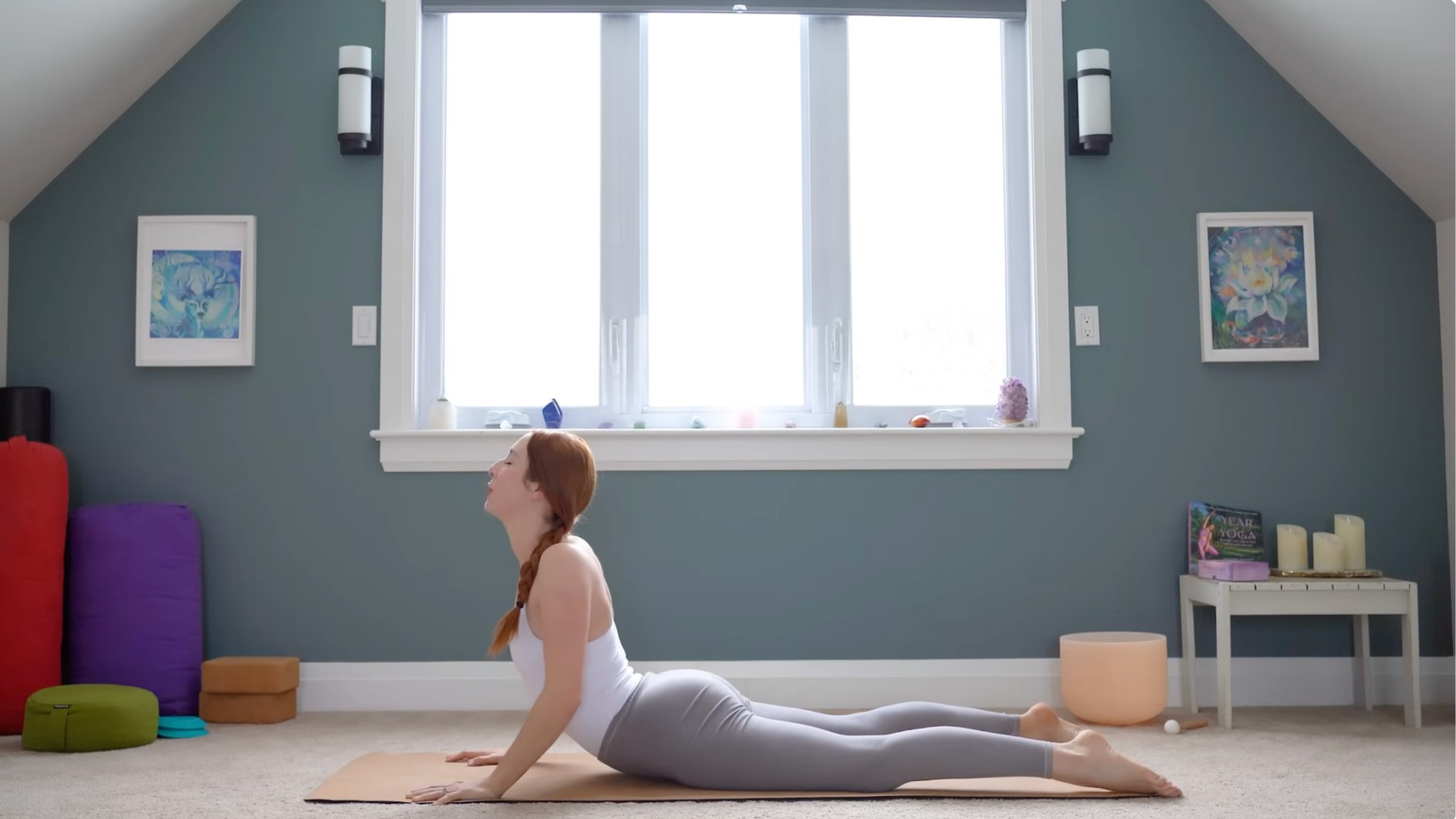 Woman lying on her belly and lifting her chest in Cobra Pose during a 15-minute yoga for upper back practice