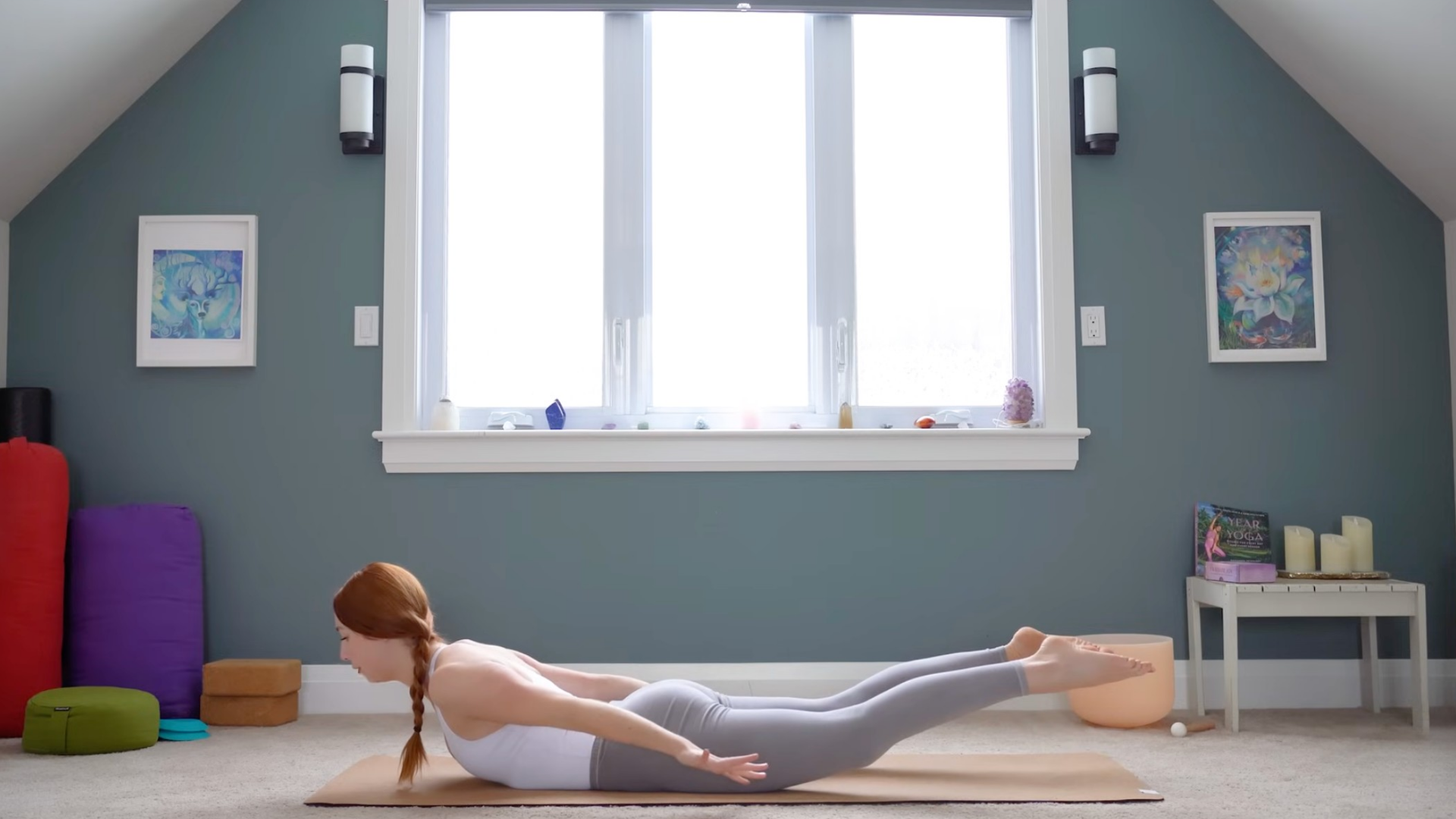 Woman lying belly down on a mat with arms and legs lifted in Locust Pose
