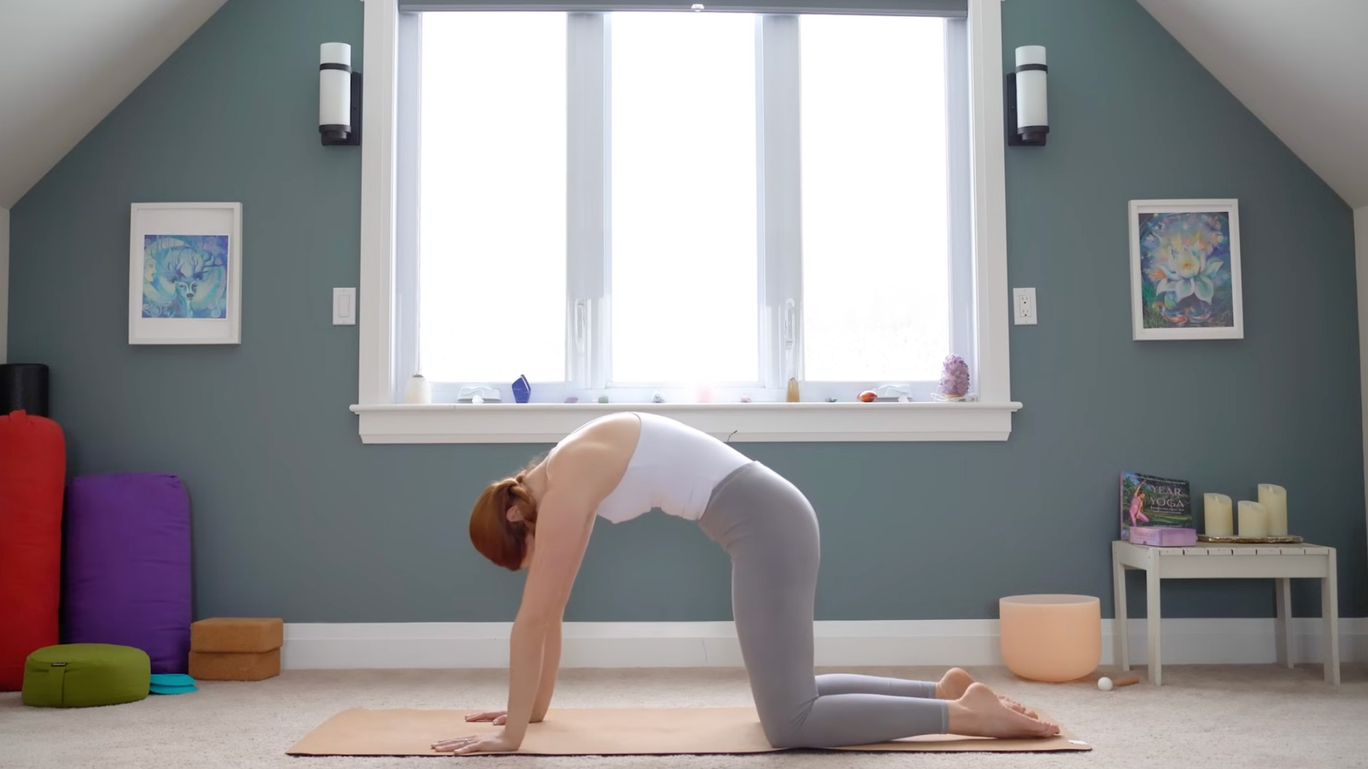 Woman on hands and knees rounding her back in Cat Pose