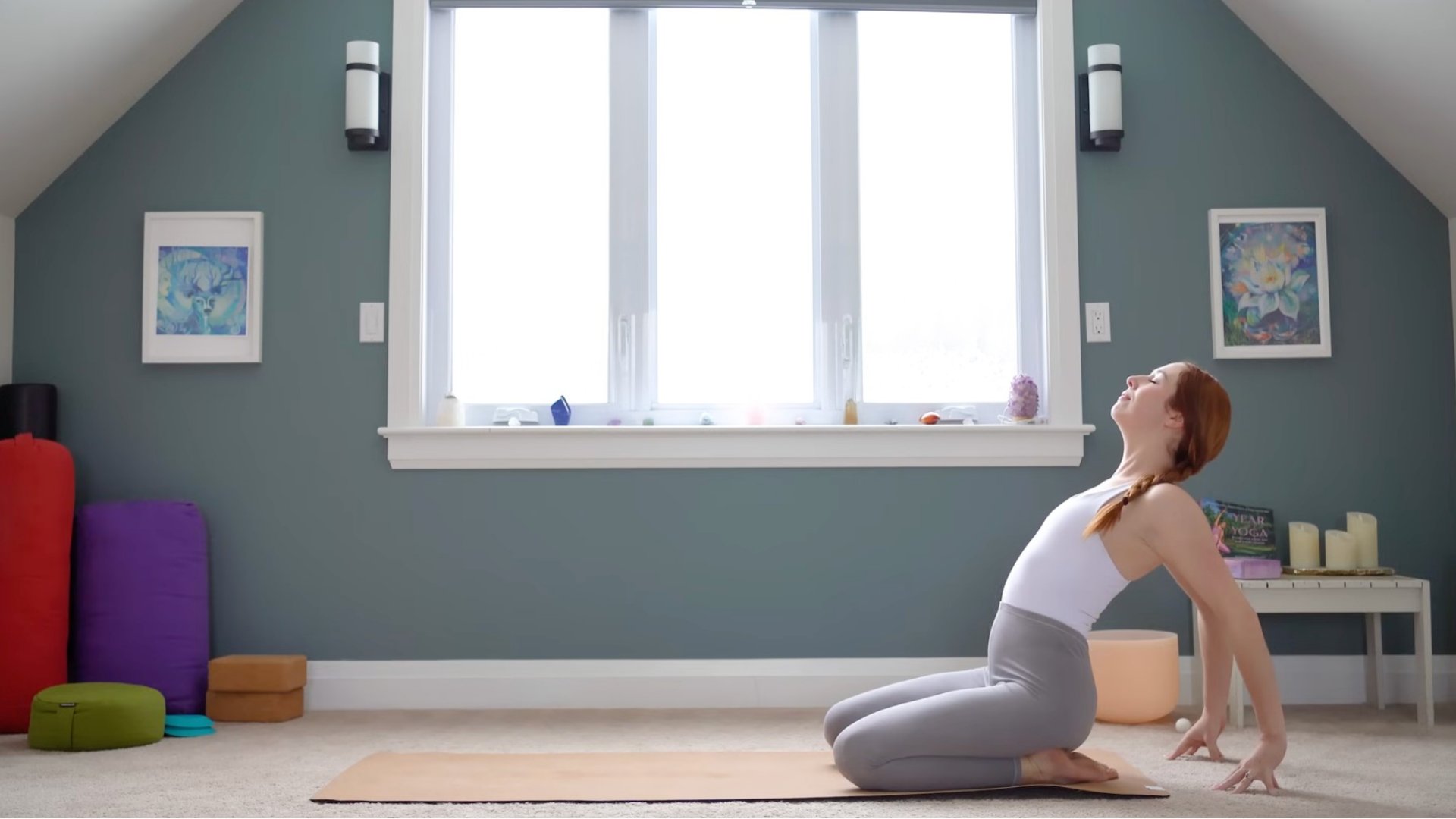 Yoga teacher kneeling on a mat with her hands behind her in a backbend.