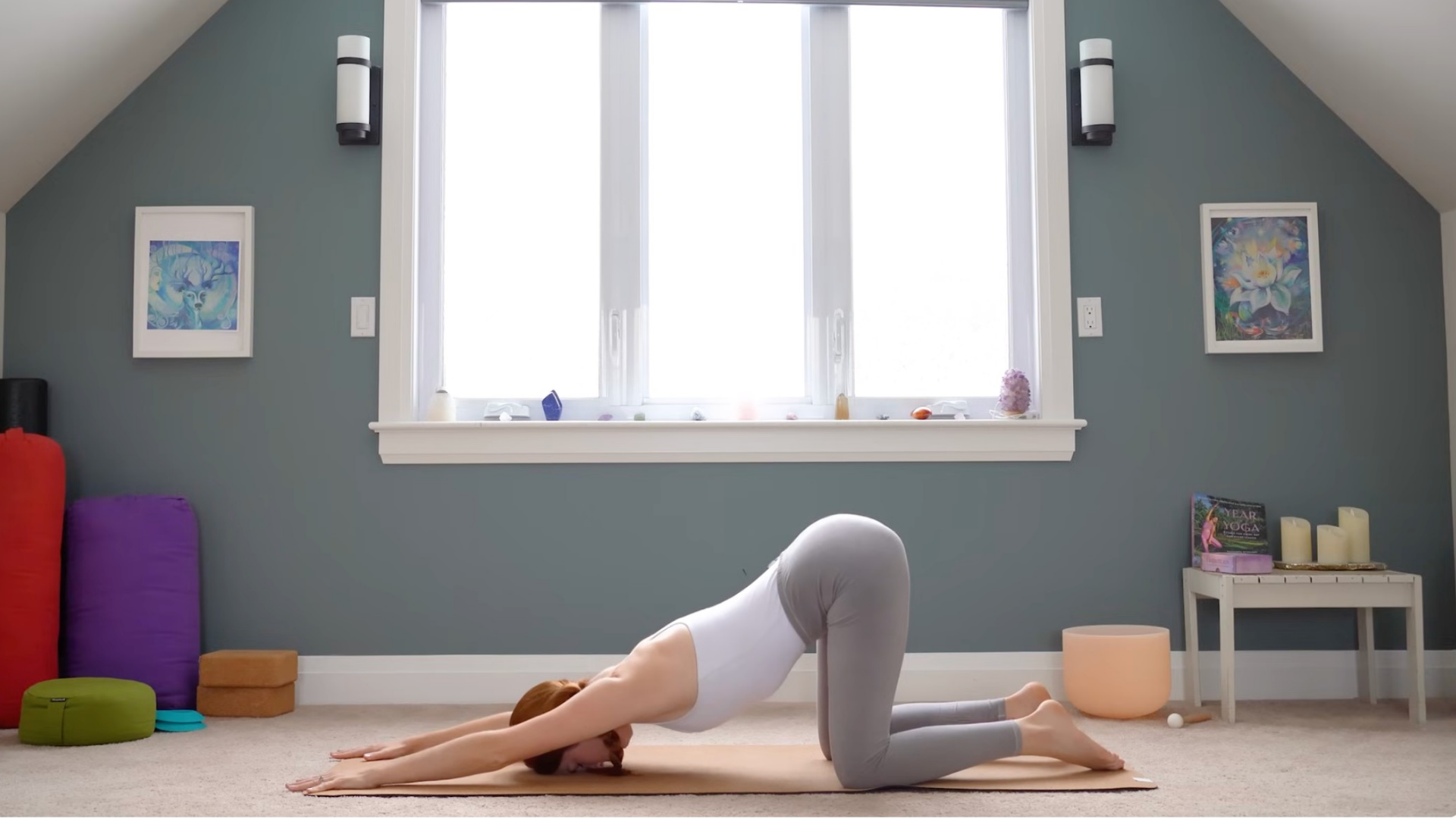 Woman kneeling on a yoga mat with her arms outstretched in Puppy Pose
