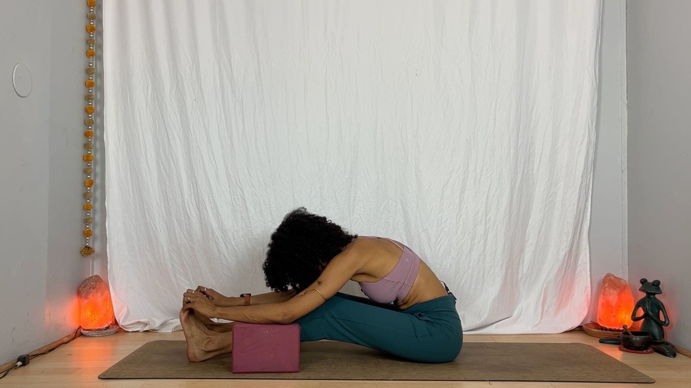 A yoga instructor practices a seated forward fold exercise.