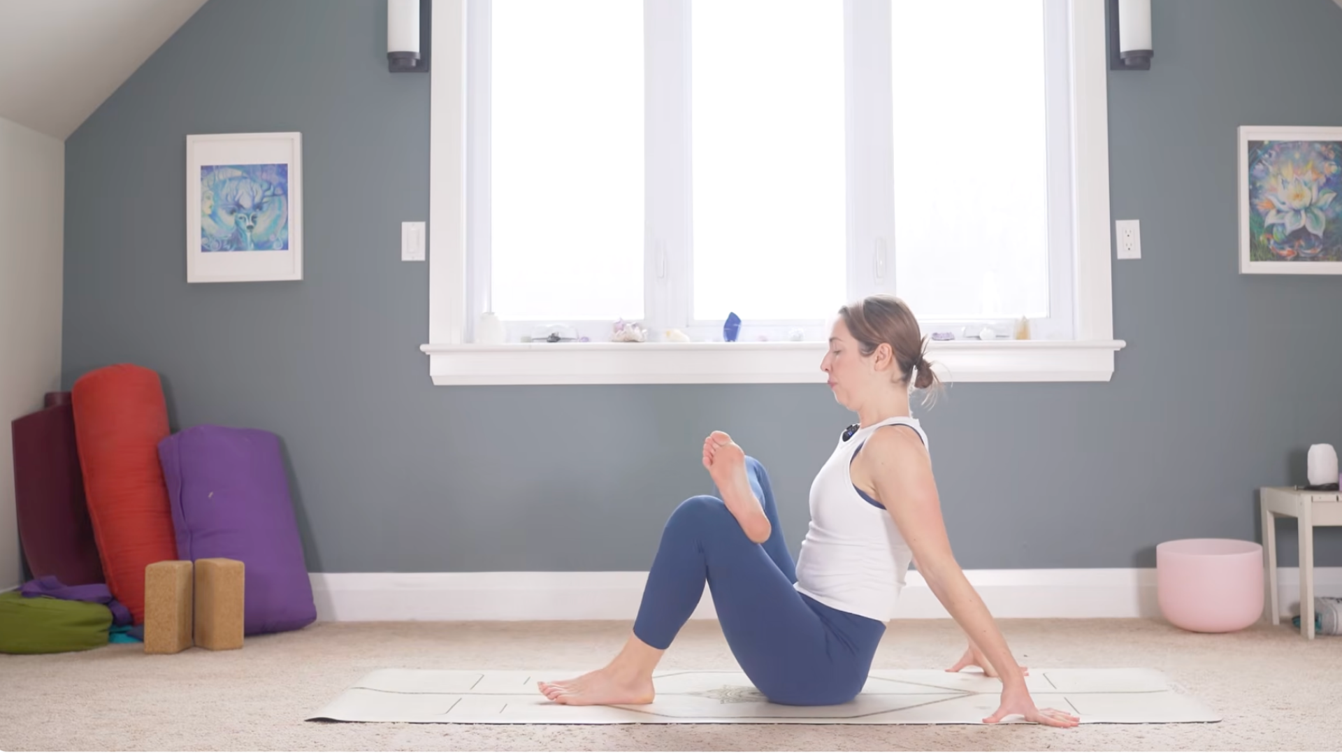 Woman sitting on a mat with her hands behind her in a seated version of Pigeon Pose