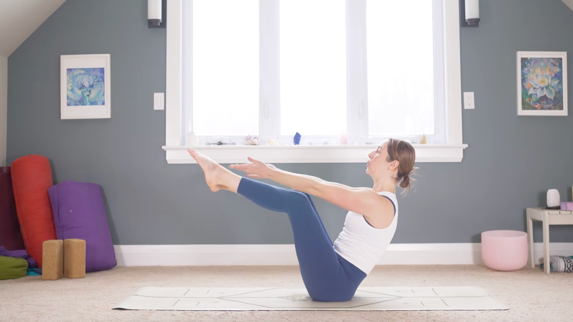 Woman sitting back on her sit bones while reaching her arms forward in Boat Pose
