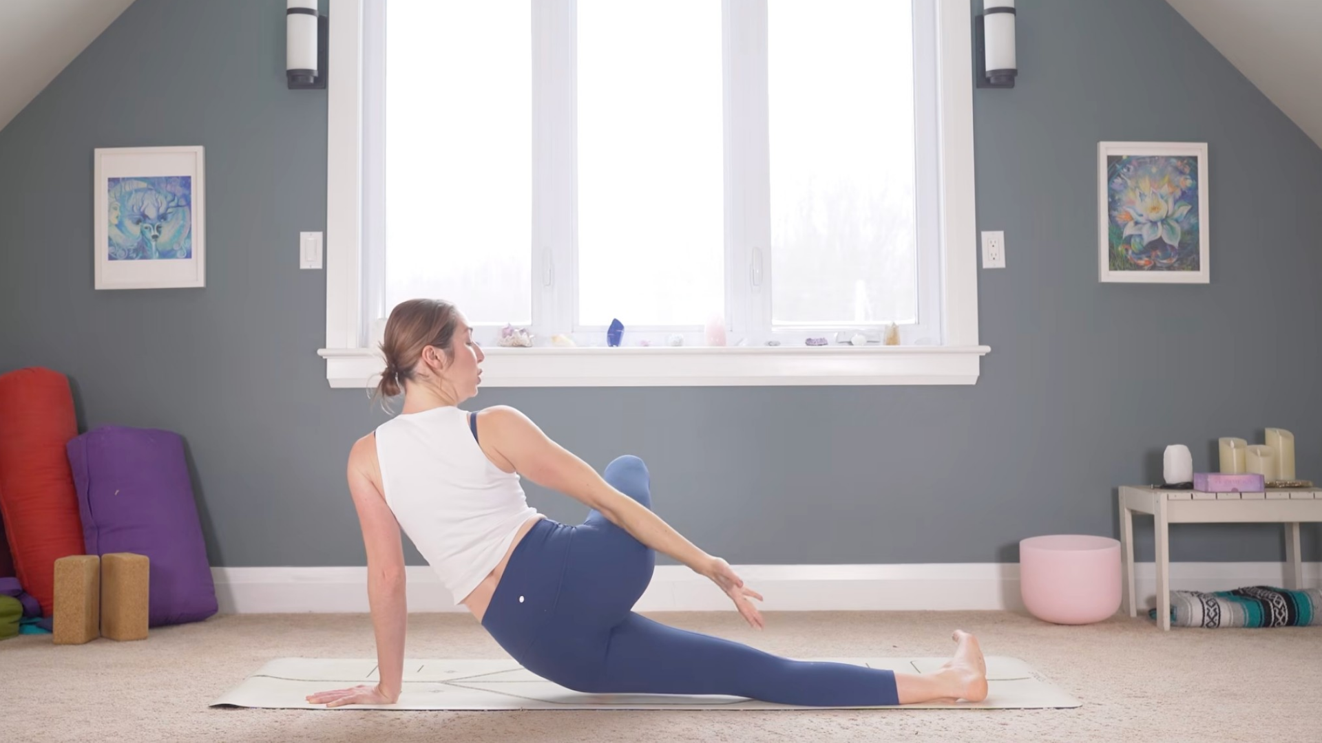 Woman leaning her left hip on a yoga mat and reaching her right arm behind her
