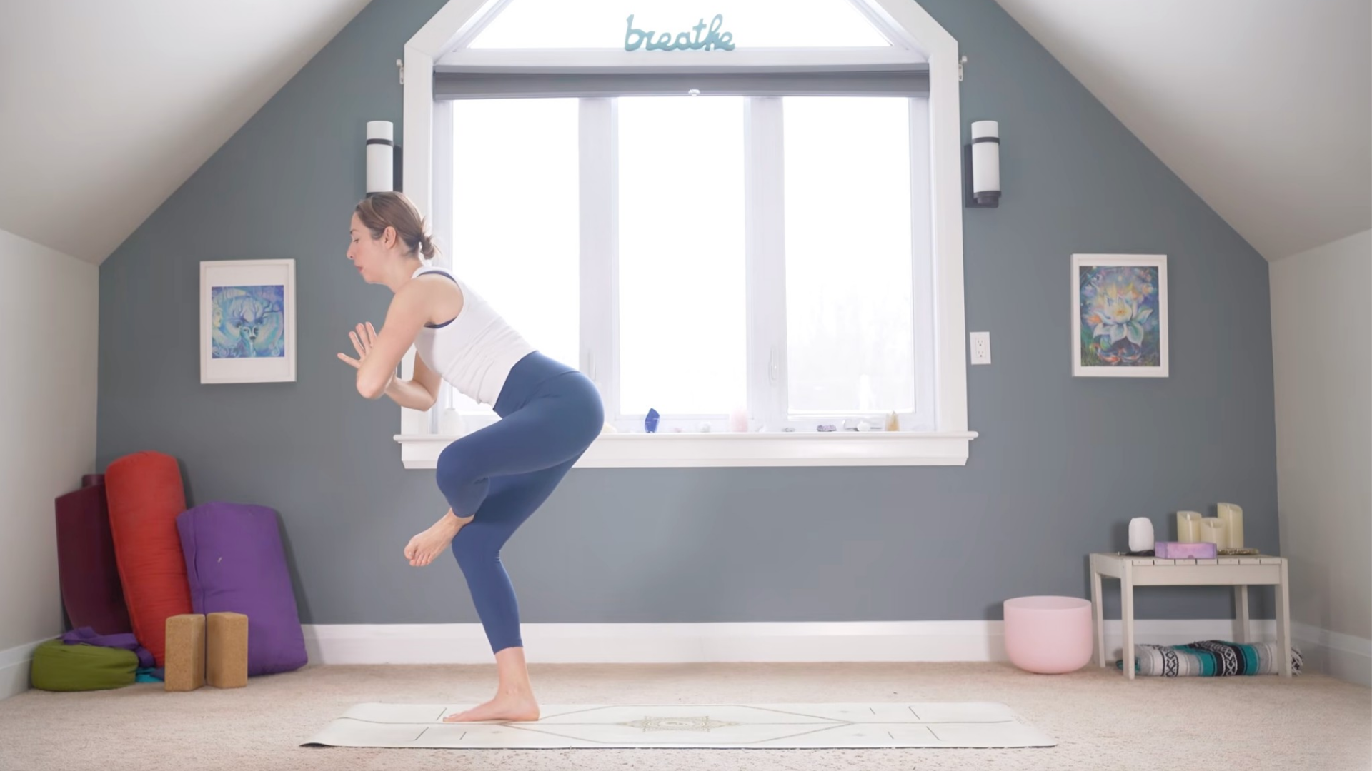 Woman standing in Chair Pose with one ankle crossed over her opposite thigh in a figure-4 or standing pigeon pose