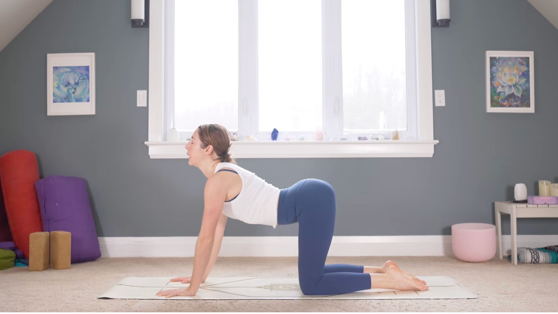 Woman kneeling on a yoga mat with her back arched