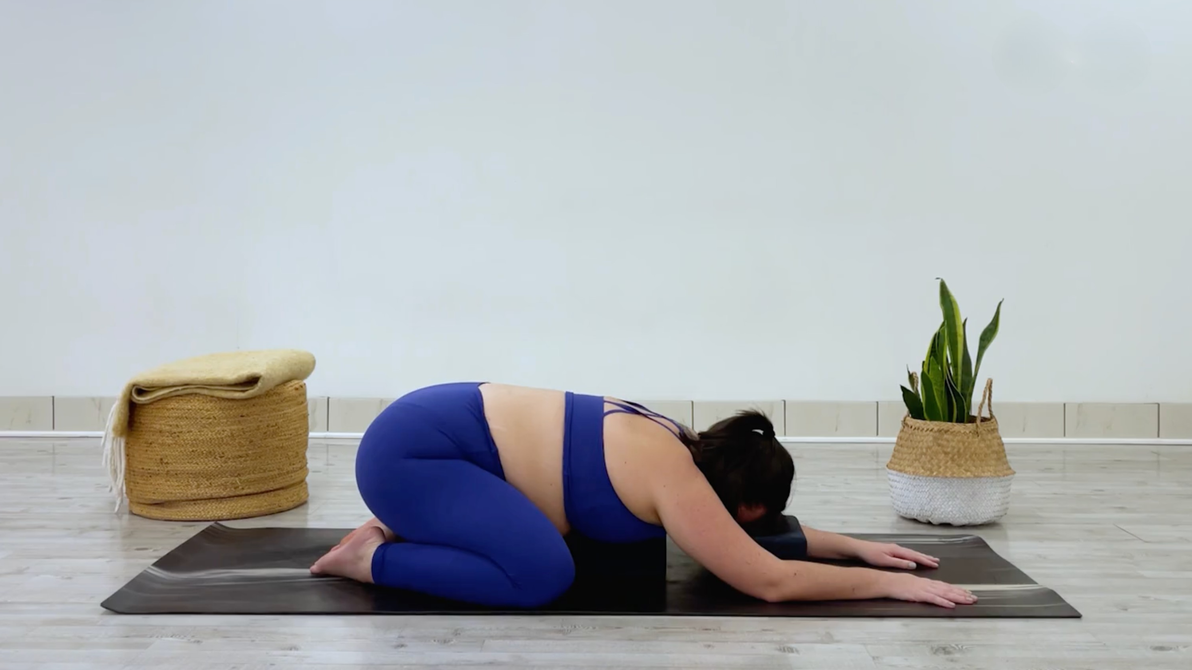 Yoga teacher Taylor Lorenz poses in child's pose, a yin yoga pose to stretch her inner thighs