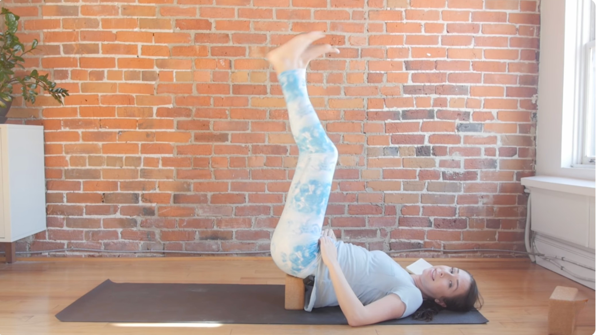 Woman with her legs reaching into the air during a yin yoga for throat chakra practice