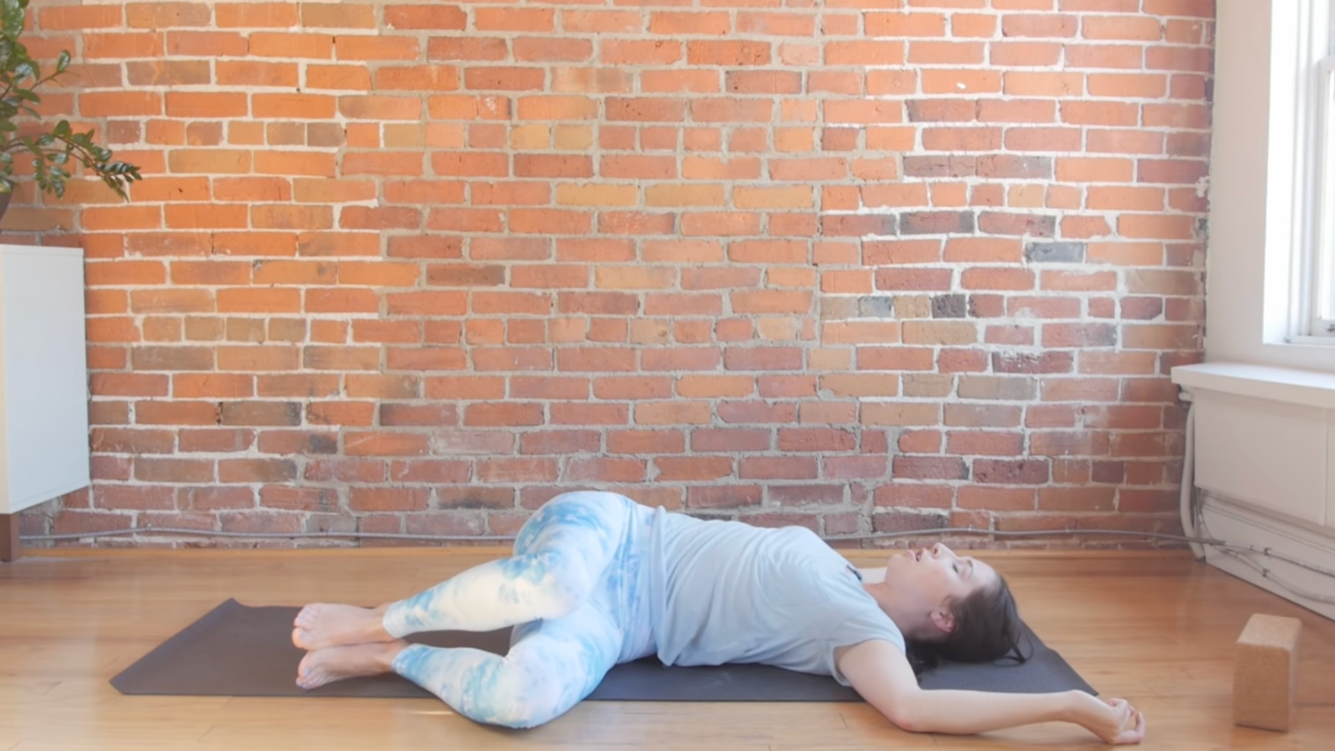 Woman lying on her back in a twist during a yin yoga for throat chakra practice
