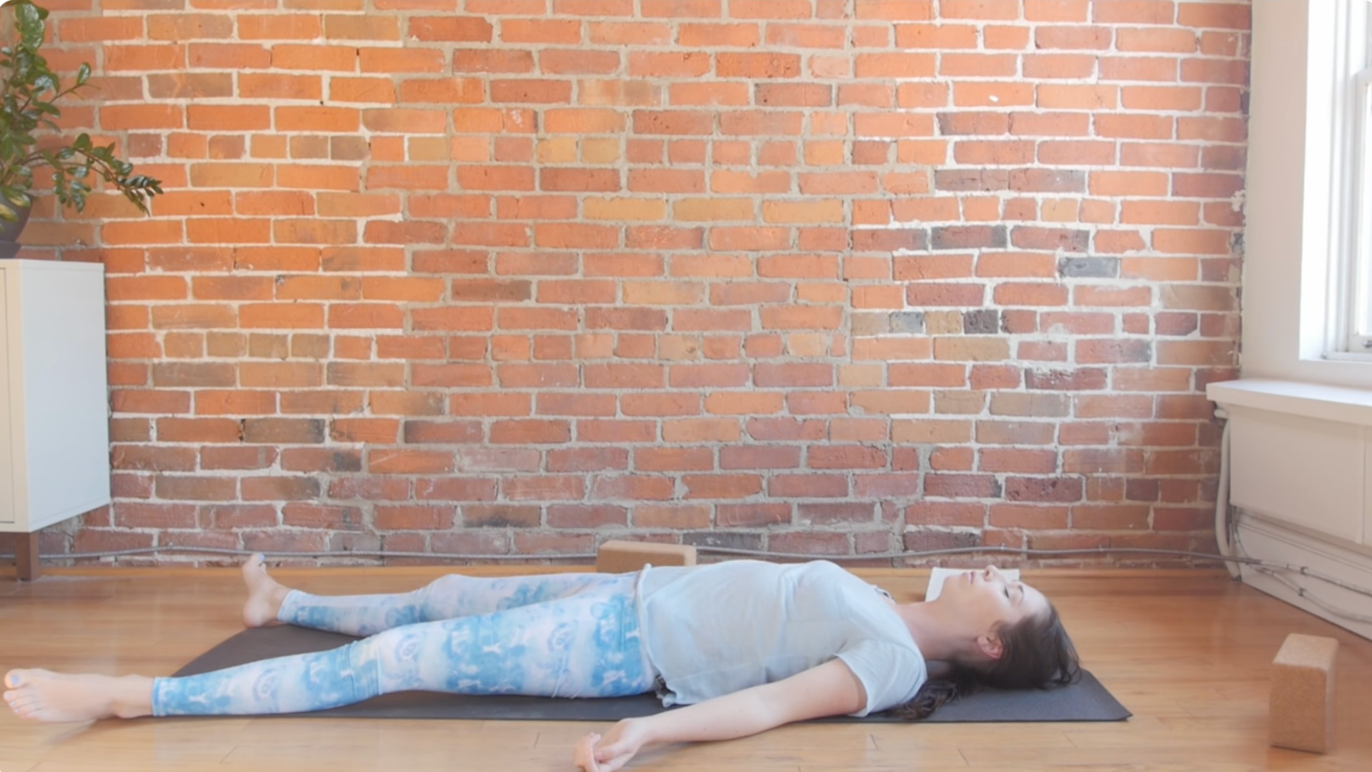 Woman lying on her back on a mat in Savasana