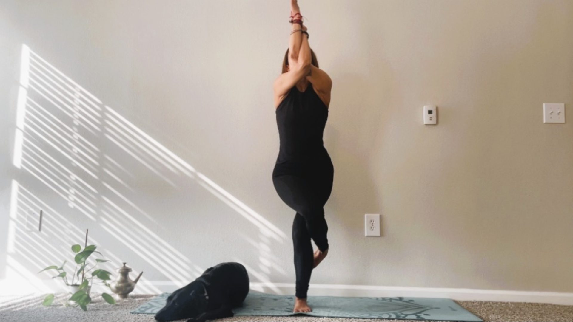 Woman balancing in Eagle Pose with her legs and arms crossed in front of her during a yoga for freeze response practice