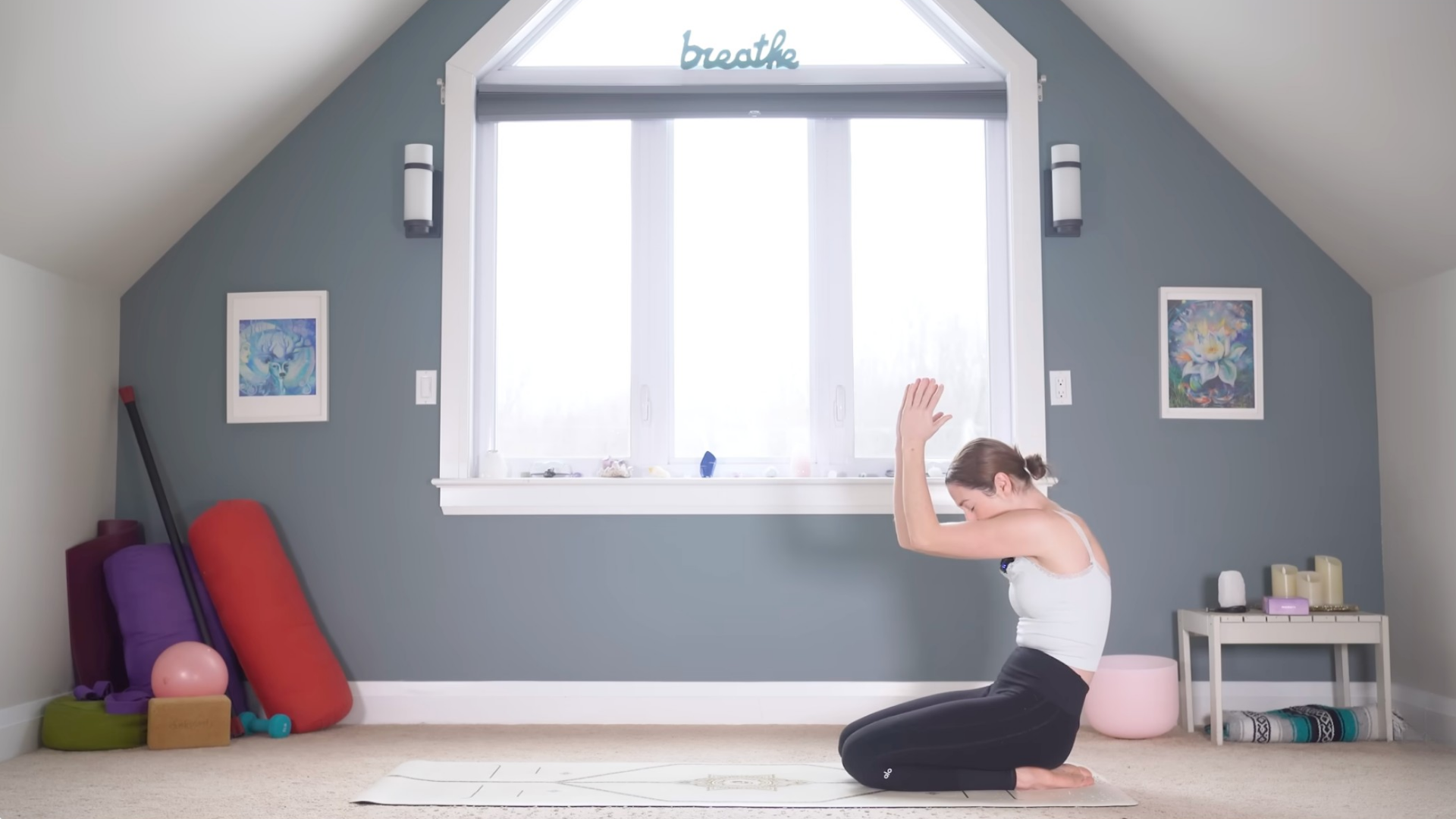 Woman kneeling on a yoga mat and bringing her elbows together while rounding her back