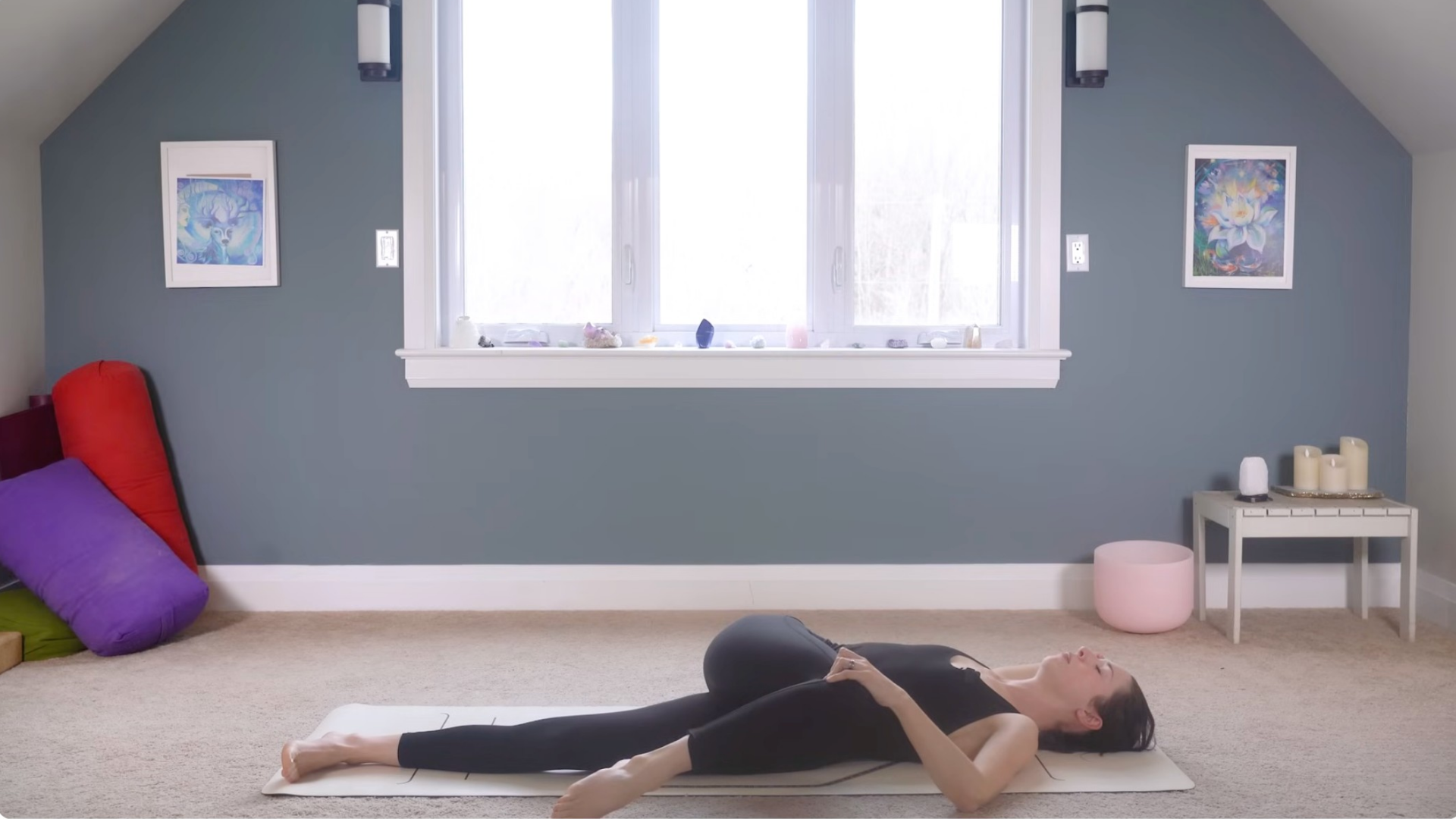 Woman lying on her back on a mat and twisting toward the left