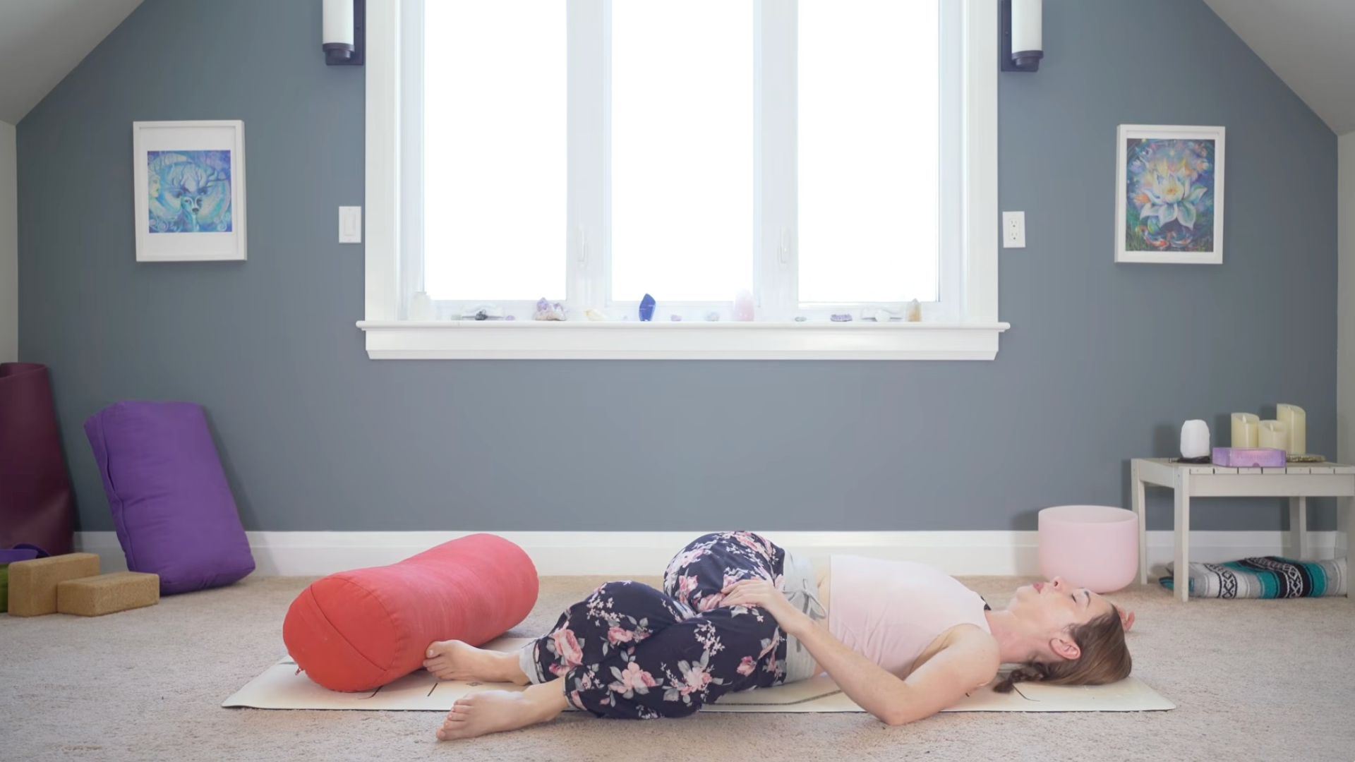 Woman lying on a at in a reclined twist during a yin yoga for exhaustion practice