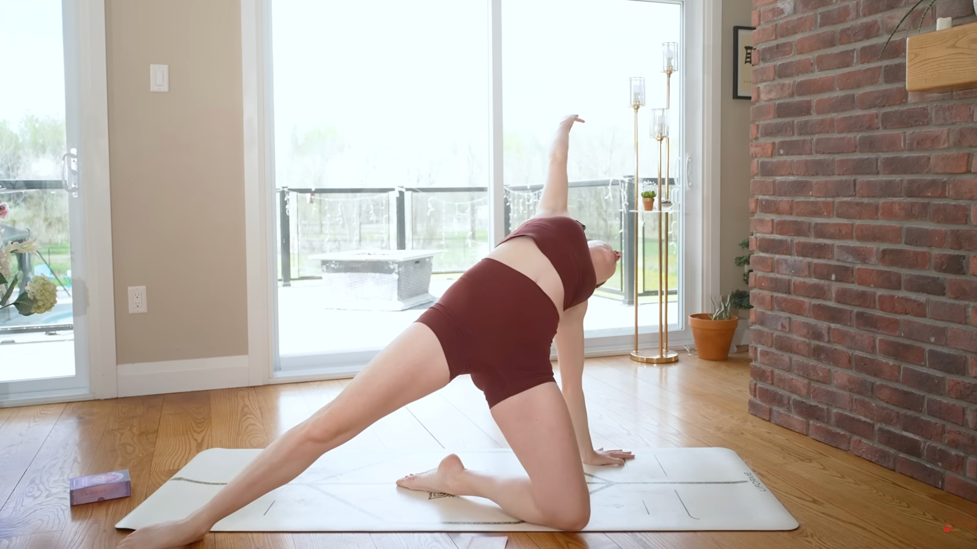 Woman kneeling on the mat with one arm outstretched in Baby Wild Thing