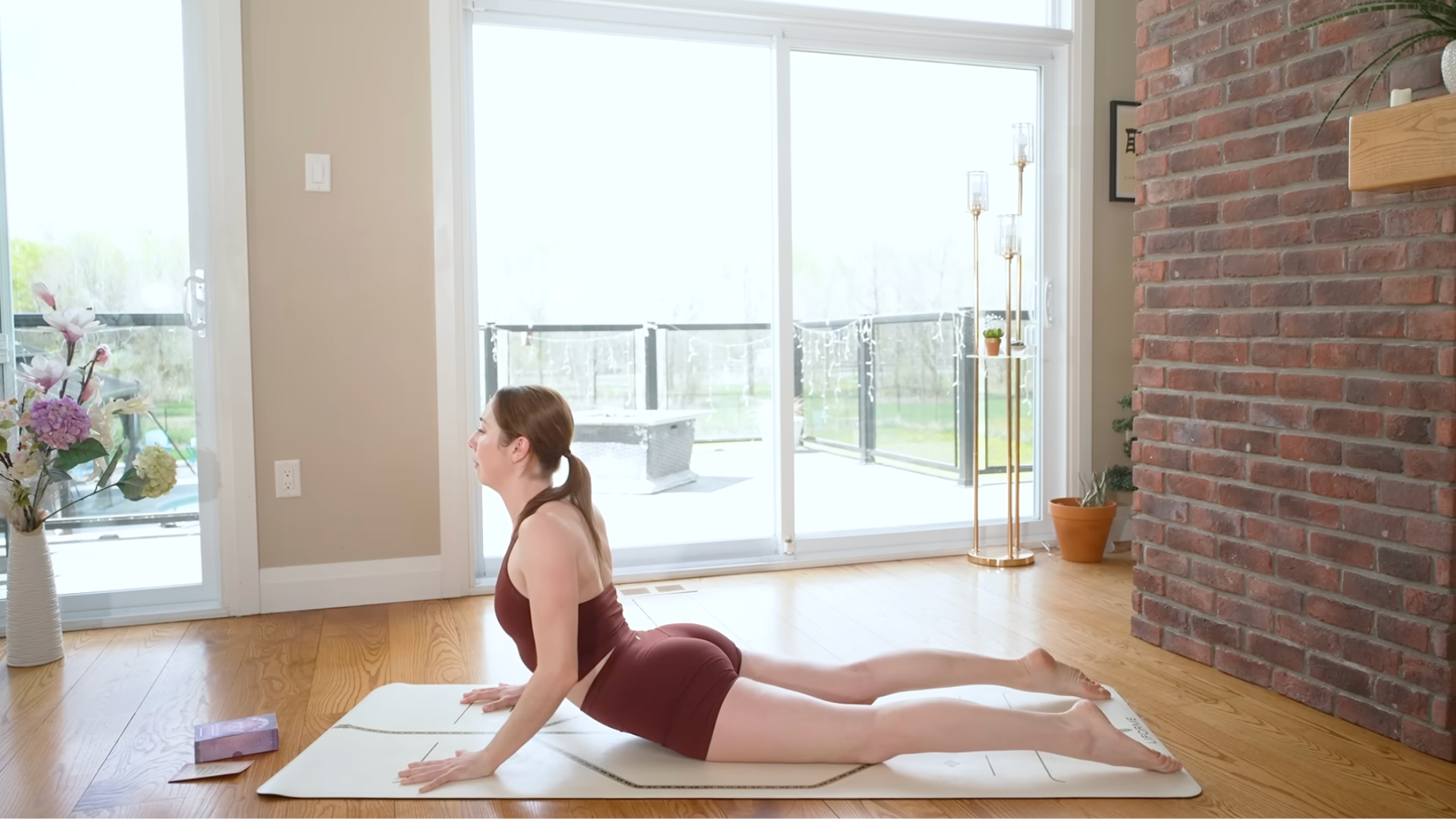 Woman lying on her belly on a yoga mat while pressing her hands into the mat and lifting her chest in Cobra Pose