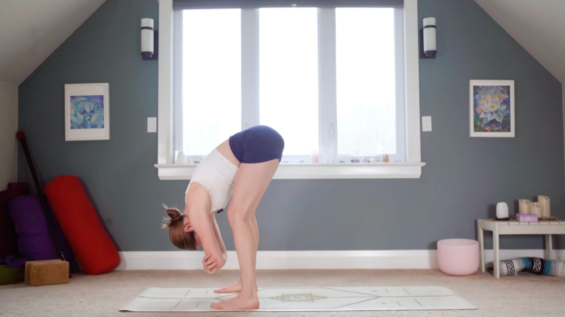 Woman in a Standing Forward Bend holding opposite elbows at the front of the mat