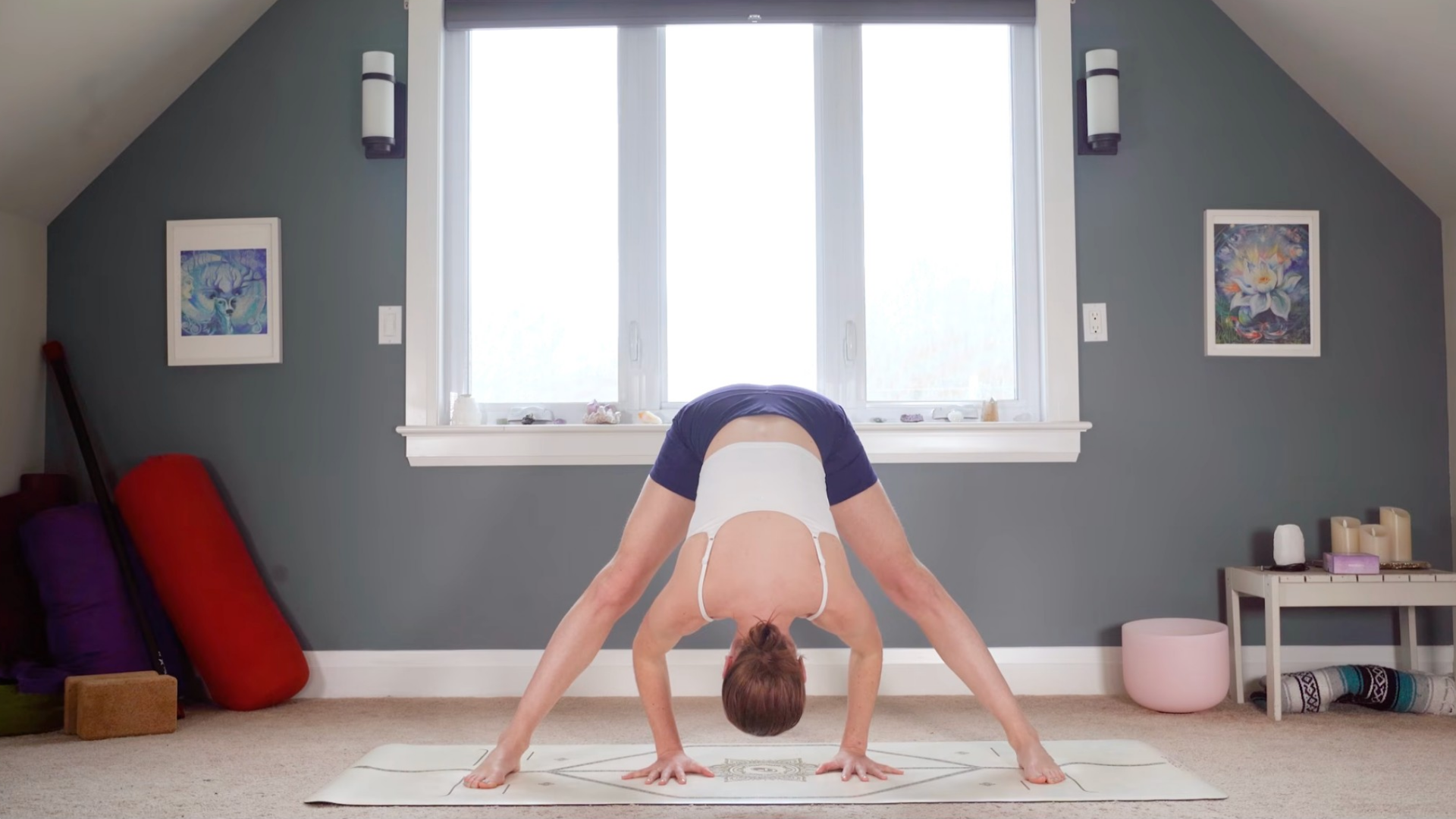 Woman in a Wide-Legged Standing Forward Bend or Prasarita Padottanasana facing the long side of the yoga mat