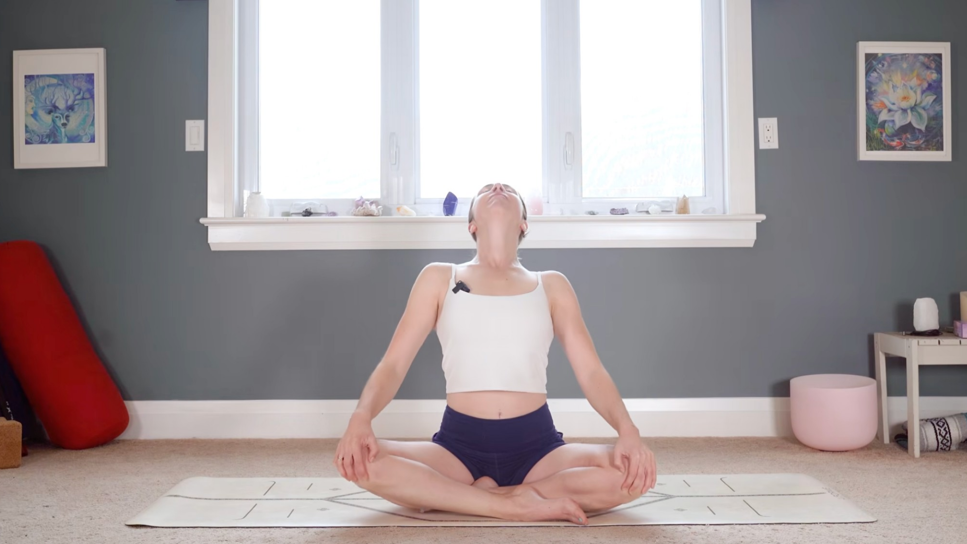 Woman sitting cross-legged on a yoga mat practicing a backbend