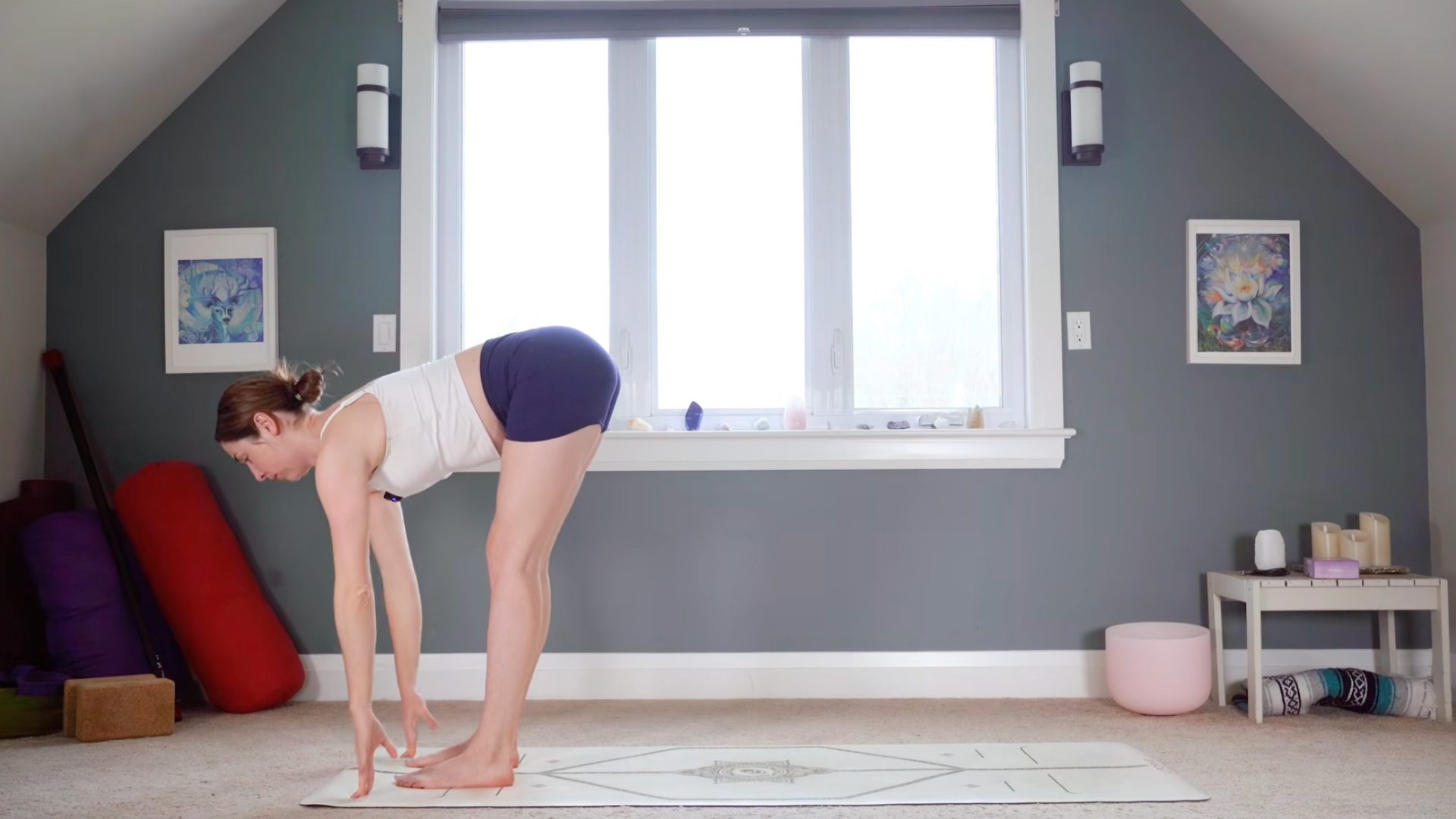 Woman in a standing forward bend but lifting her chest and back halfway to standing in Ardha Uttanasana