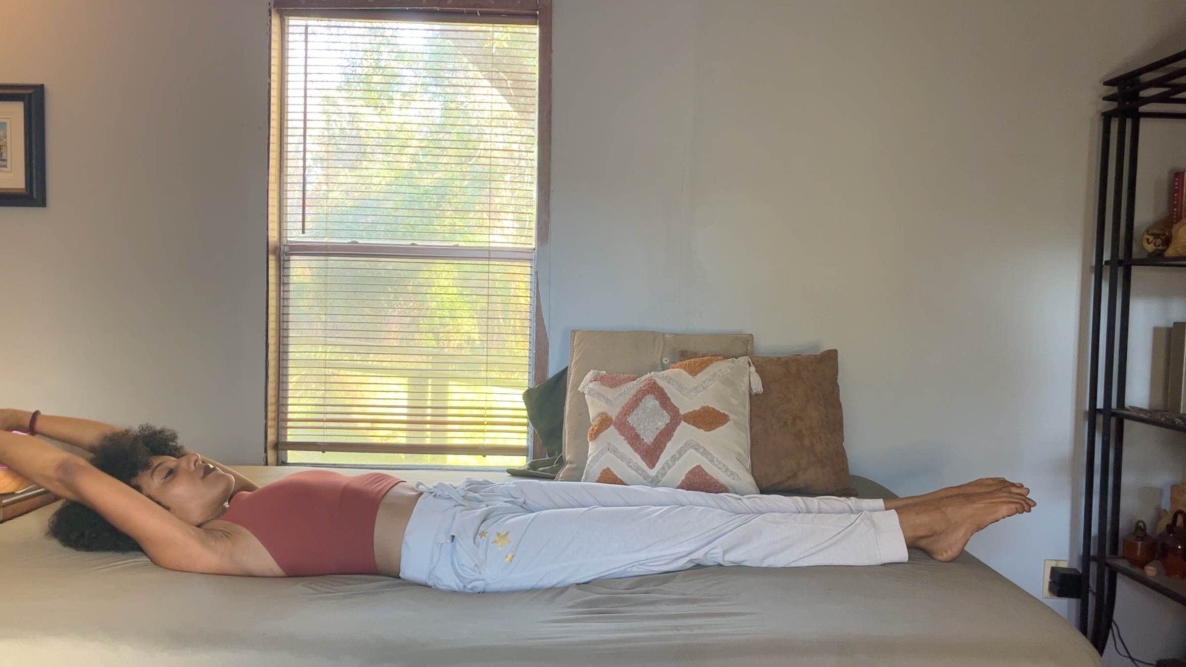 Yoga teacher practicing full-body stretch on bed.