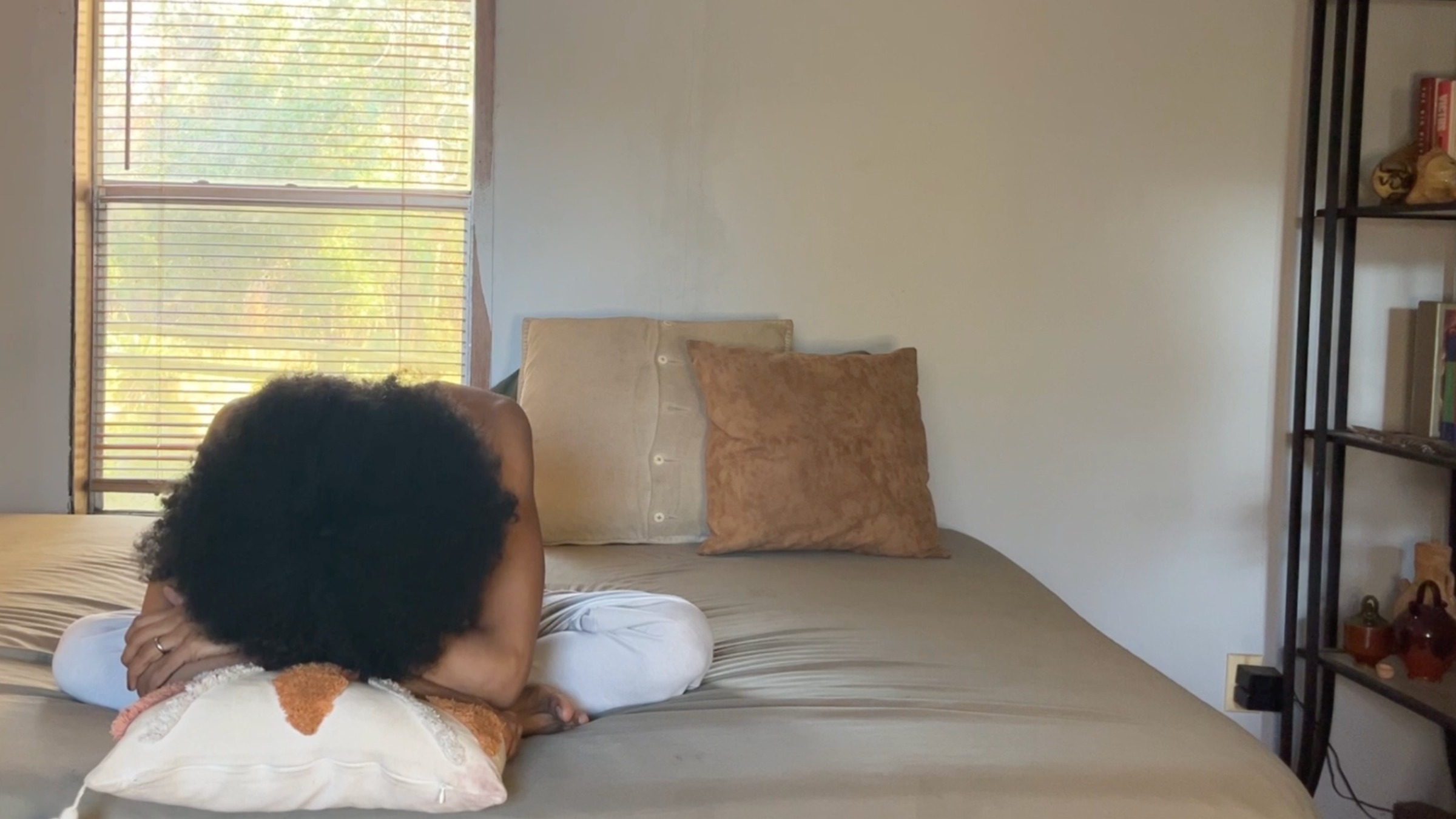 Yoga teacher practicing Seated Forward Fold variation in bed.