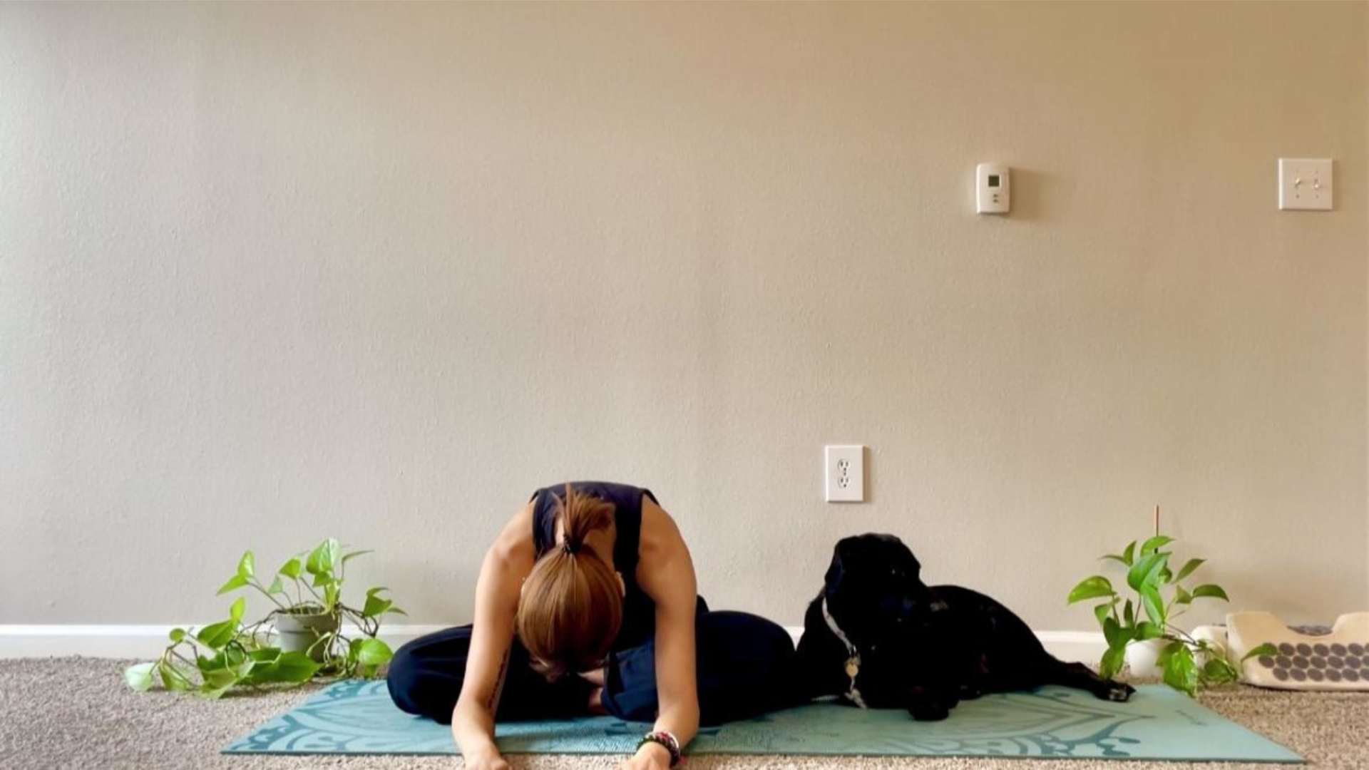 Woman sitting on a yoga mat and bending forward in a cross-legged version of Bound Angle or Baddha Konasana