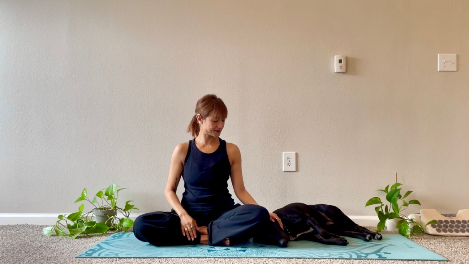 Yoga teacher sitting on her mat with her dog following a 5-minute yoga reset routine