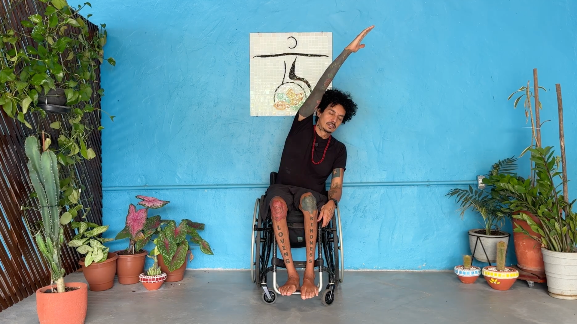 Man seated in a wheelchair reaching his left arm overhead as he leans toward the right