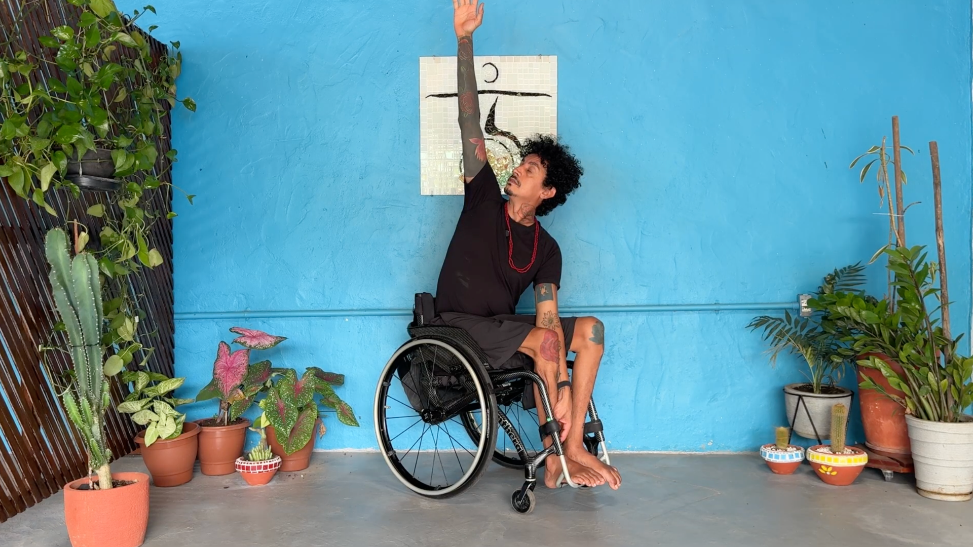 Man sitting in a wheelchair reaching his right arm toward the ceiling in a seated variation of Trikonansa or Triangle Pose
