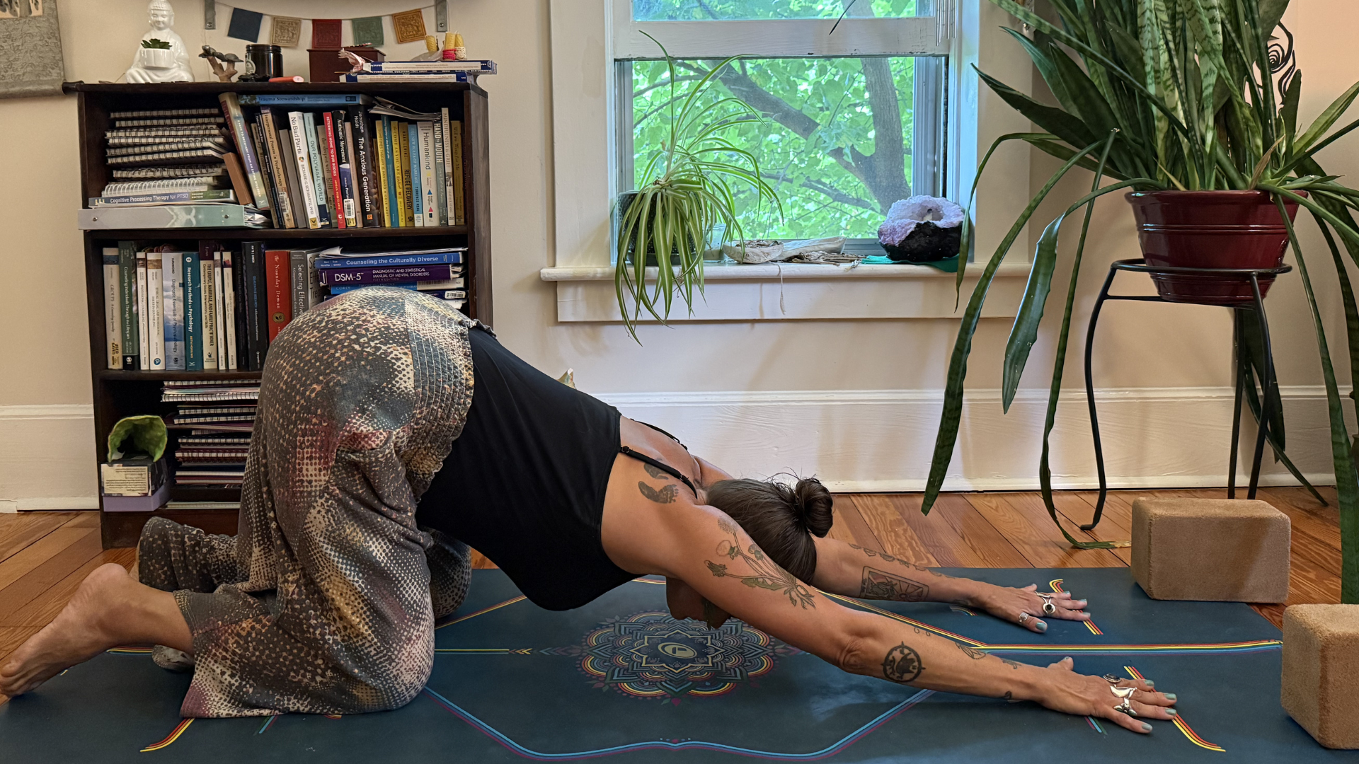 Woman kneeling on a yoga mat during a heart-opening yoga practice with her arms extended forward toward the front edge of the mat in Puppy Pose (Anahatasana).