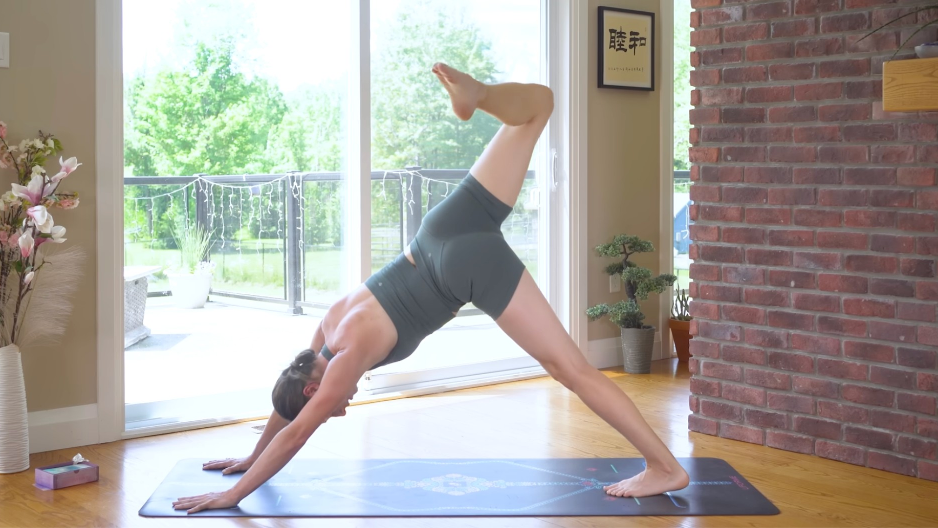 Woman on a yoga mat in Three-Legged Dog with one leg lifted and her knee bent to stretch the hip flexors in a yoga for core strength routine