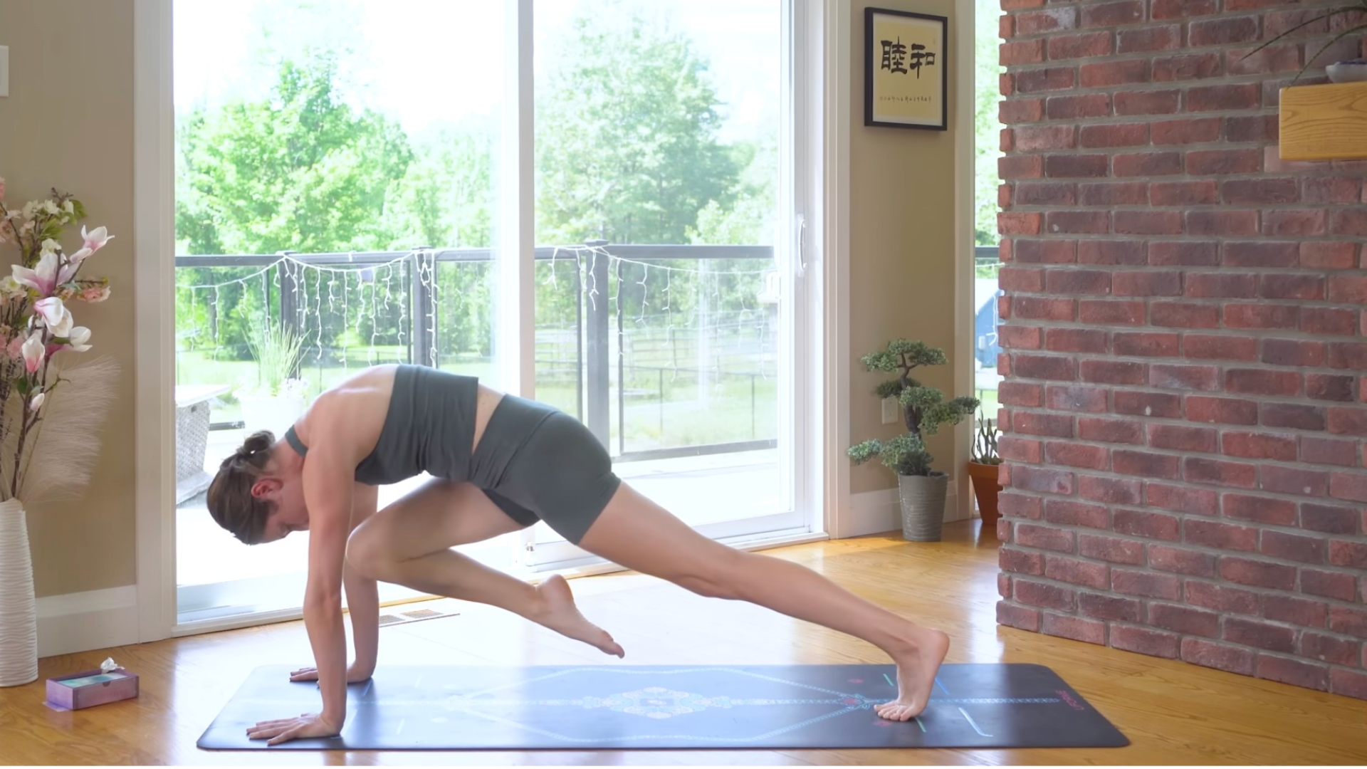 Woman practicing Knee to Nose following Three-Legged Dog on a yoga mat
