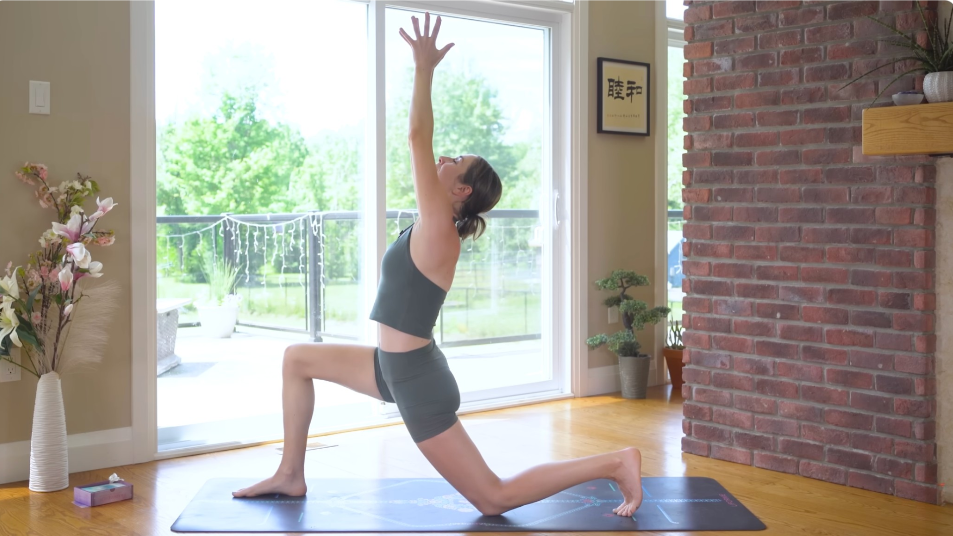 Woman kneeling on a mat in Low Lunge while looking up at her hands in a slight backbend