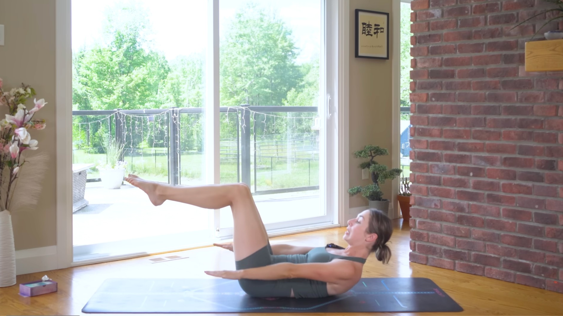 Woman lying on her back and lifting her knees and shoulders while pumping her arms during the Pilates classic, The Hundred