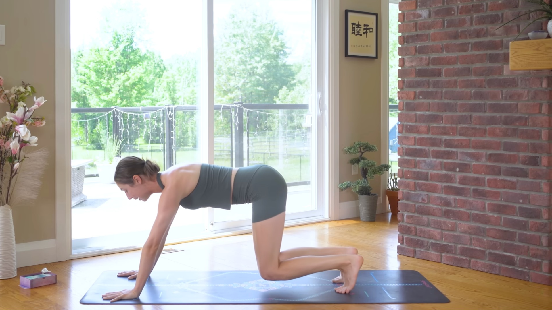 Woman hovering over her mat in a version of Tabletop that lifts the knees off the mat for during a yoga for core strength routine
