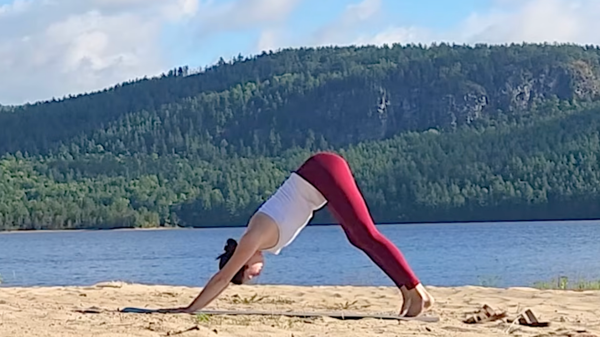 Woman in Downward-Facing Dog (Adho Mukha Svanasana) on a yoga mat with a backdrop of the Canadian wilderness