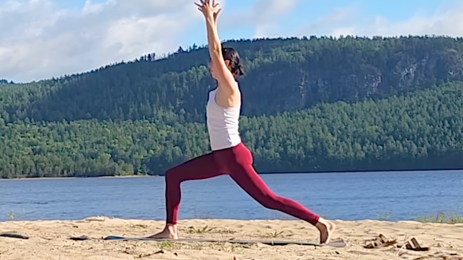 Woma in High Lunge with her feet hip-distance apart and her arms overhead during a 15-minute yoga for back routine led by Yoga With Kassandra