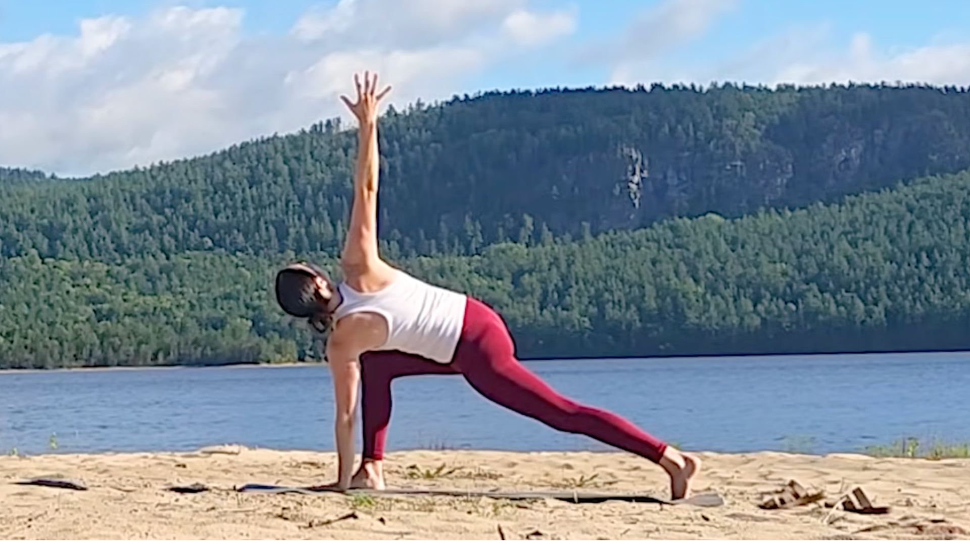 Yoga With Kassandra practicing Revolved Lunge with her left hand on the mat and her right hand reaching straight above