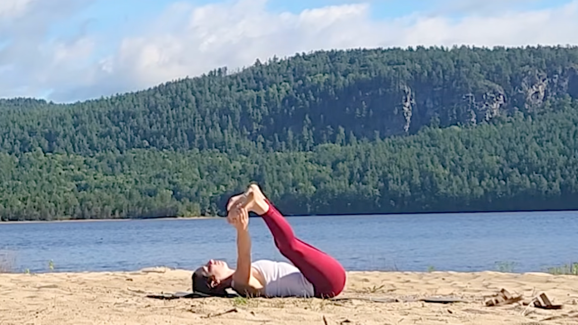 Woman during a 15-minute yoga for back practice doing a version of Happy Baby (Ananda Balasana) while straightening her legs