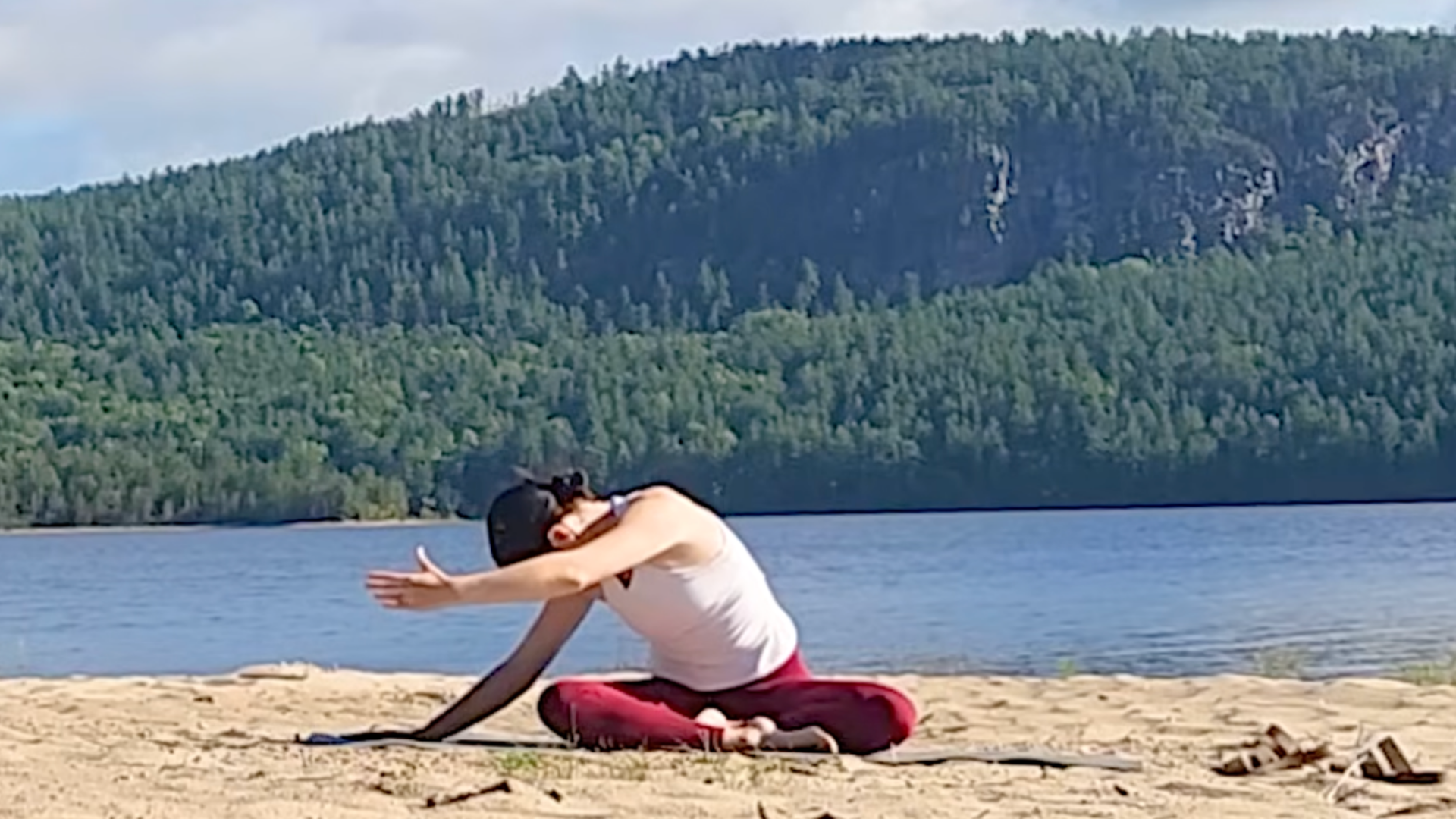 Teacher Yoga With Kassandra instructing students through a seated side bend that includes a twist