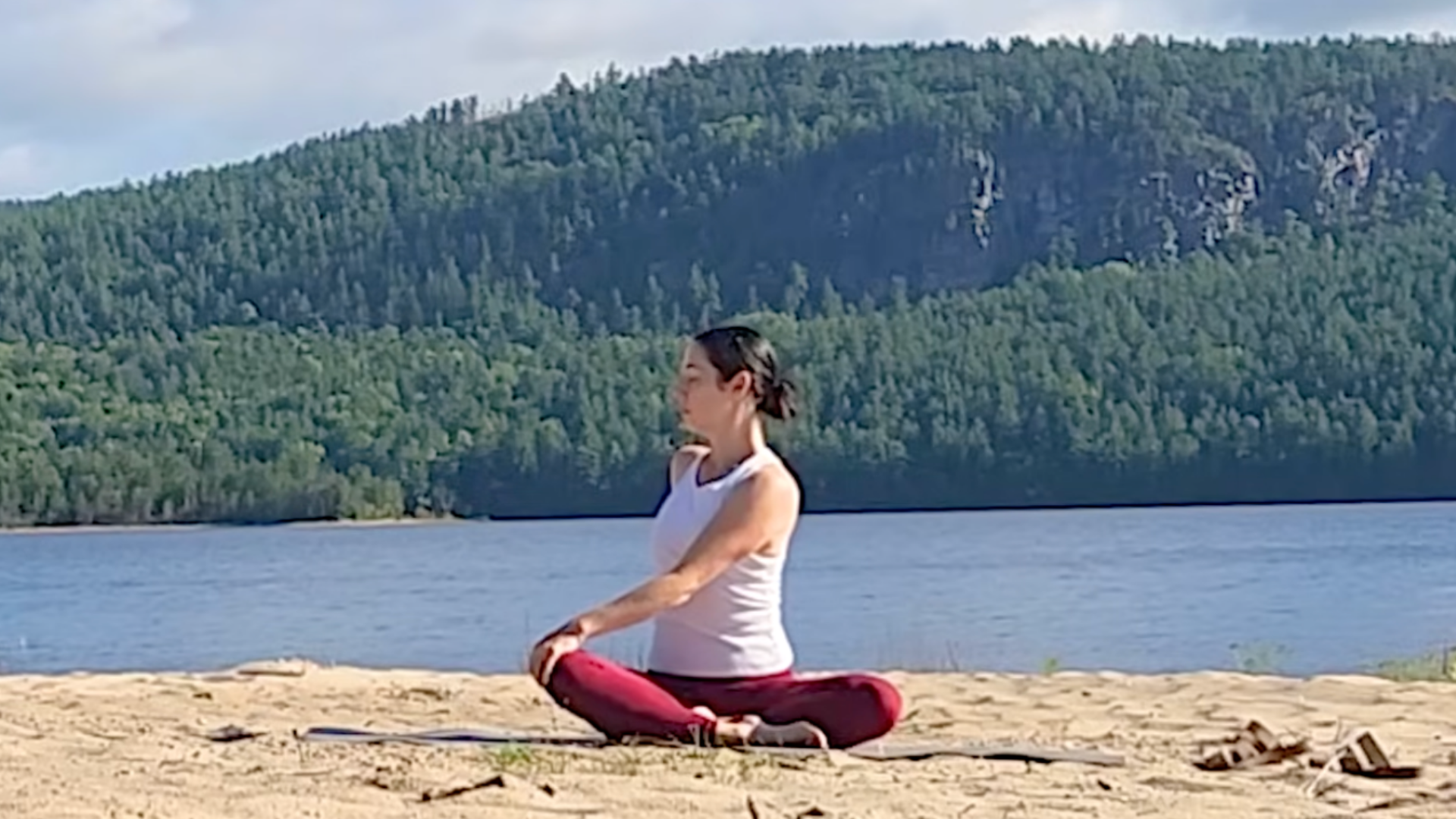 Woman sitting cross-legged during a 15-minute yoga routine for your back in which she's practicing a version of Half Lord of the Fishes or Ardha Matsyendrasana