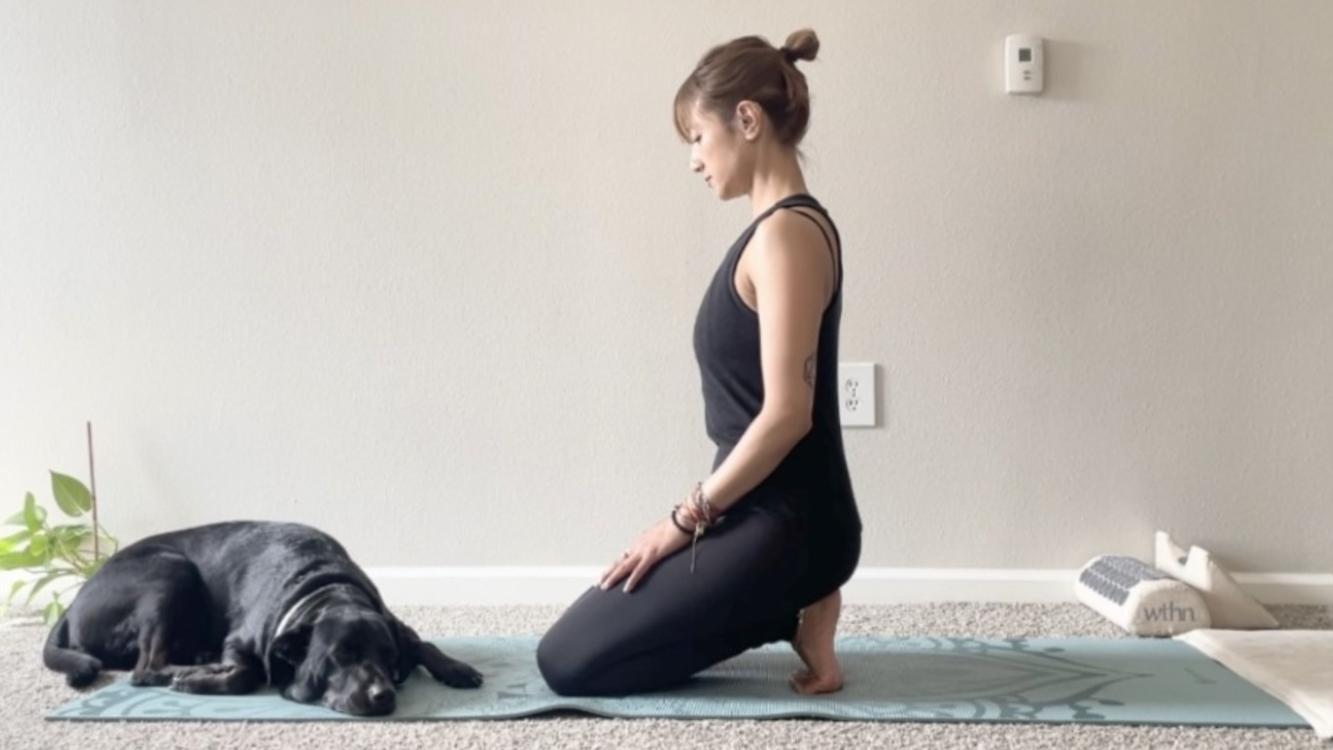 Woman kneeling on a yoga mat with her toes tucked under to stretch the plantar fascia