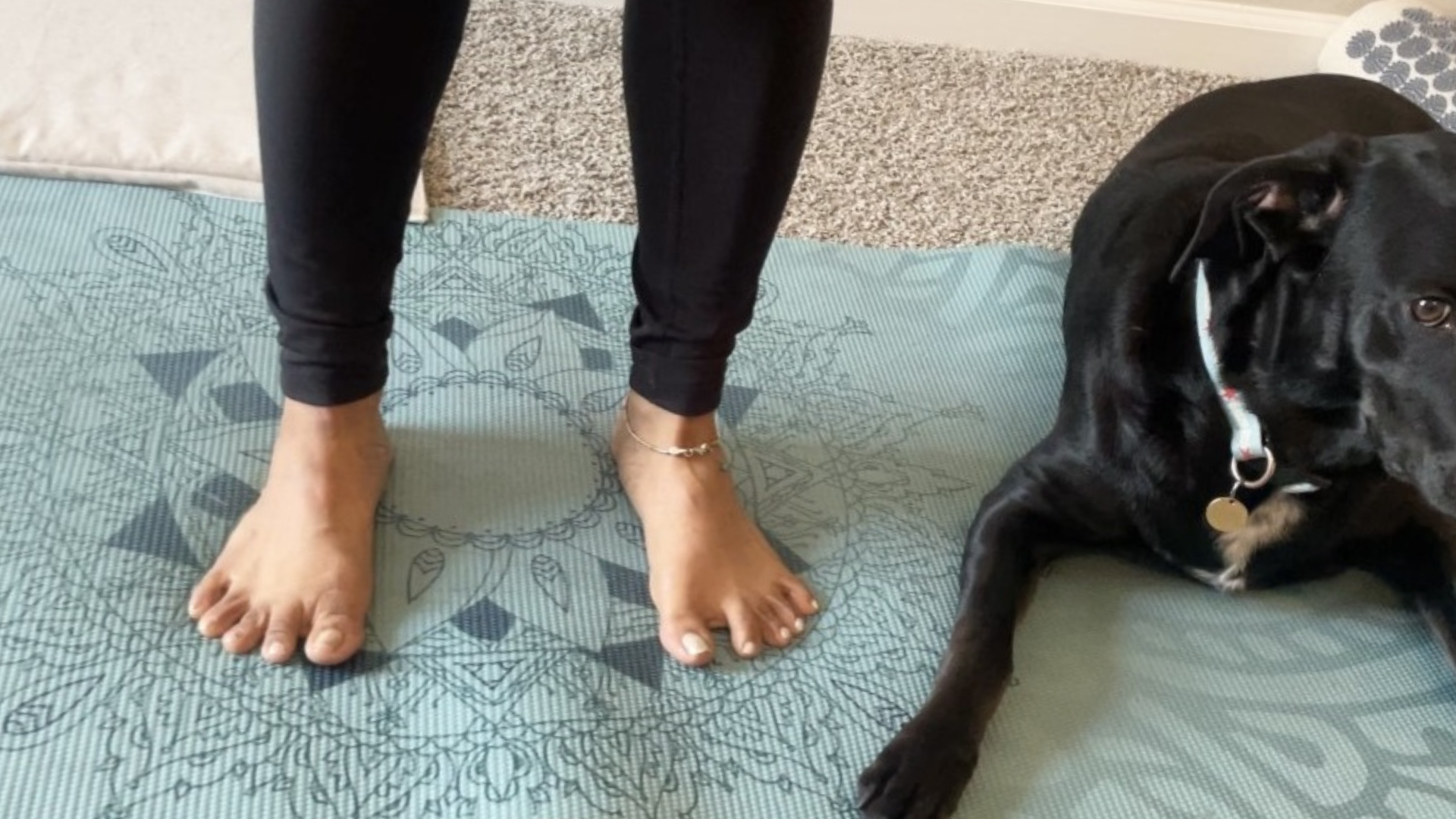 Woman standing on a yoga mat with her feet hip-distance apart in Mountain Pose (Tadasana) while lifting her arches during feet exercises