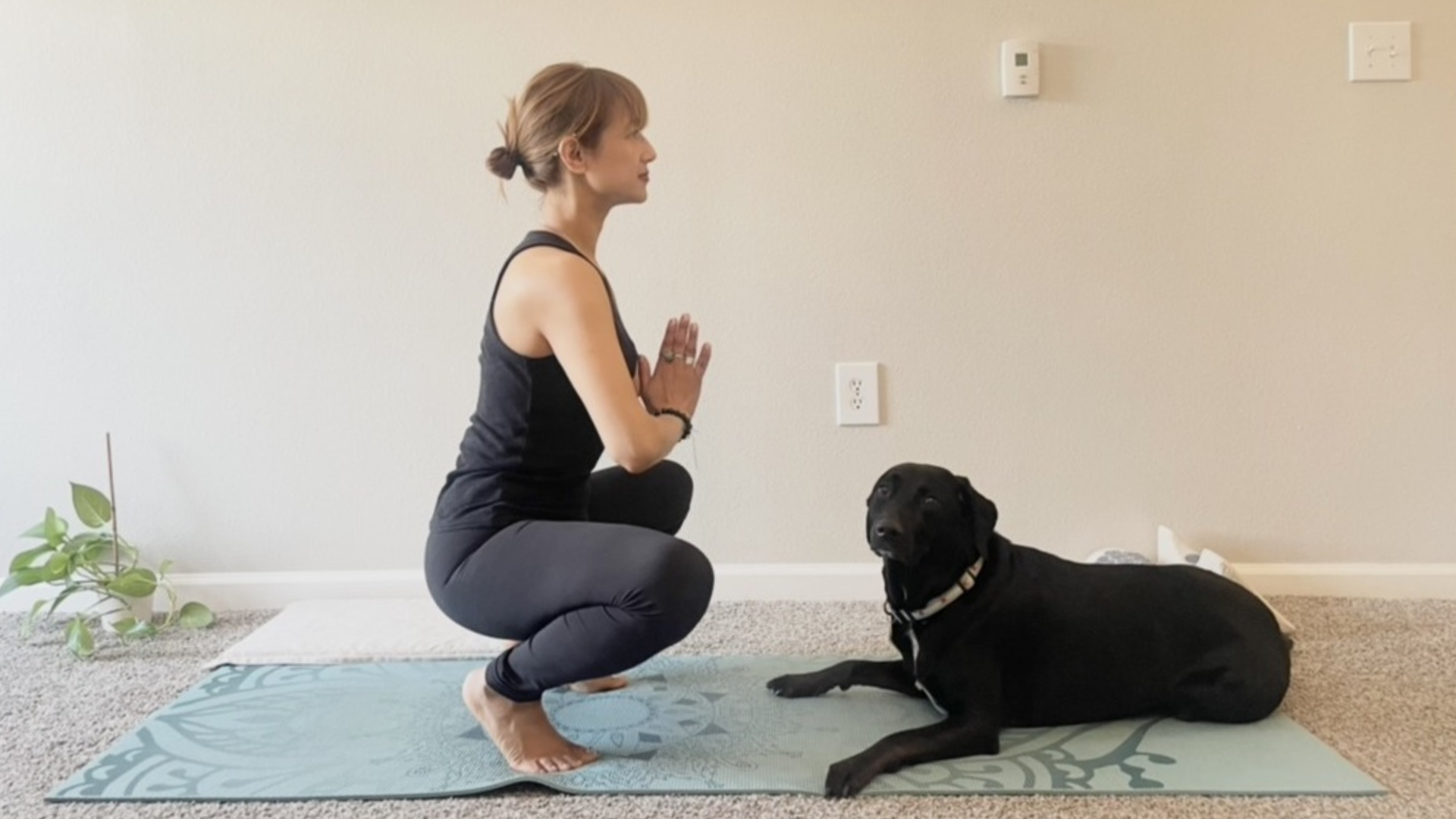 Yoga teacher performs foot exercises by raising the heels while squatting (Malasana) while balancing on a yoga mat to stretch the plantar fascia and strengthen the ankle muscles