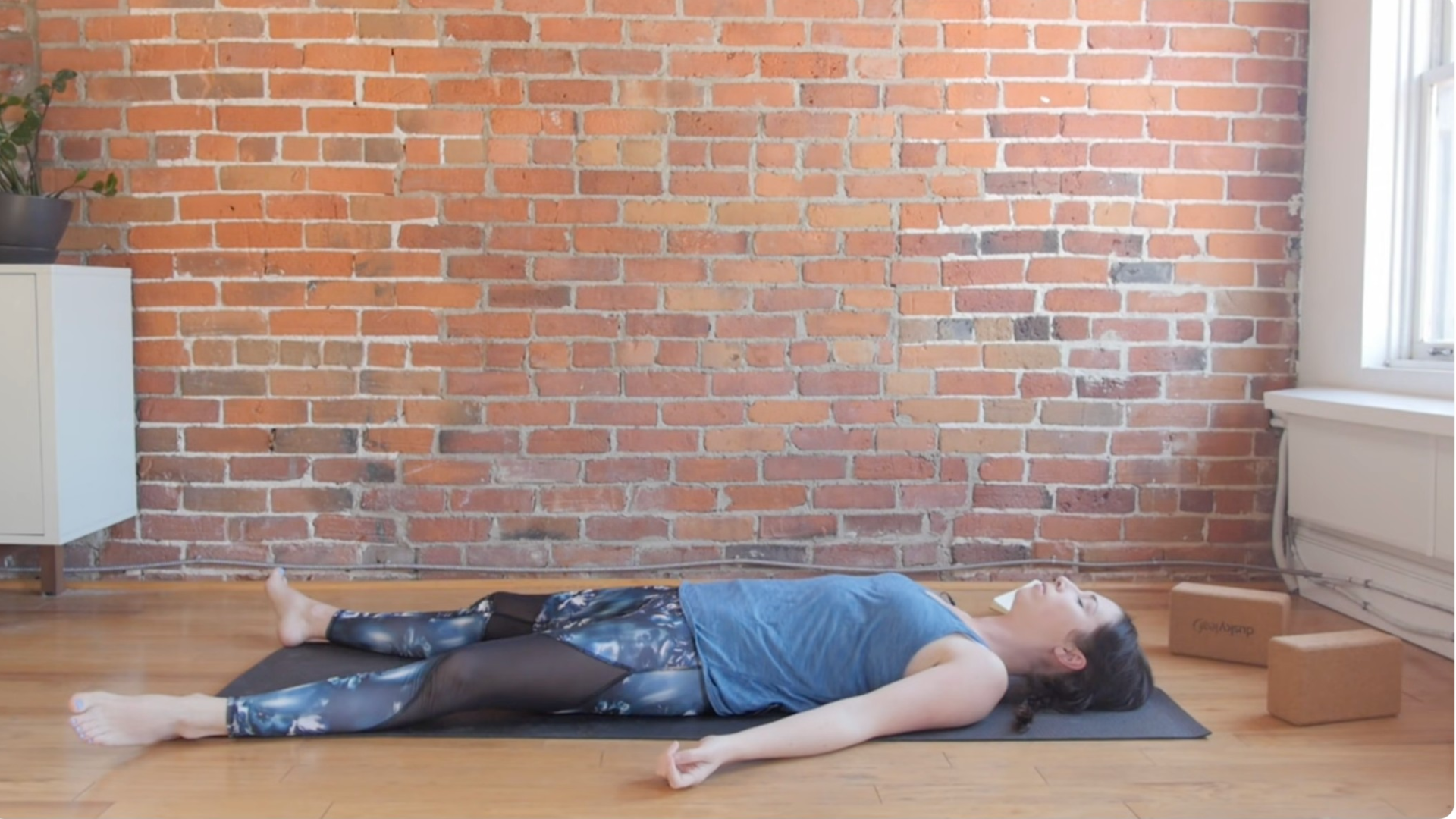 Woman lying in Savasana following a yin yoga for the third eye chakra practice