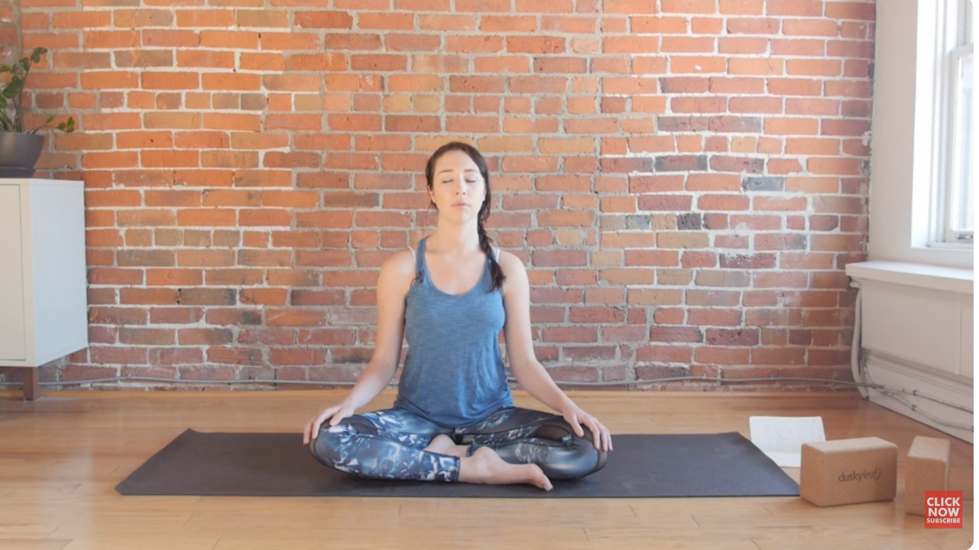 Woman sits cross-legged on a yoga mat and centers herself before teaching a yin yoga class for the third eye chakra.