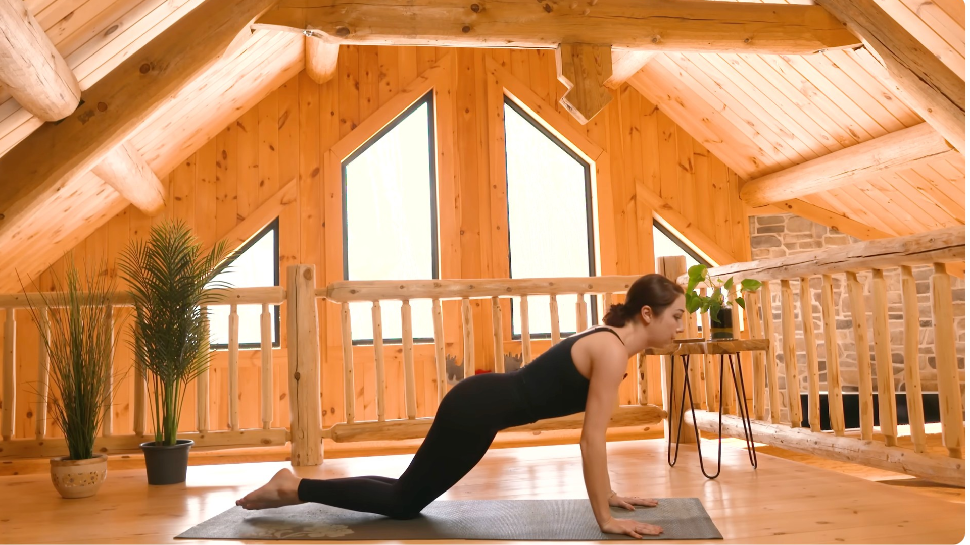 Yoga teacher kneeling on a mat in a version of plank pose